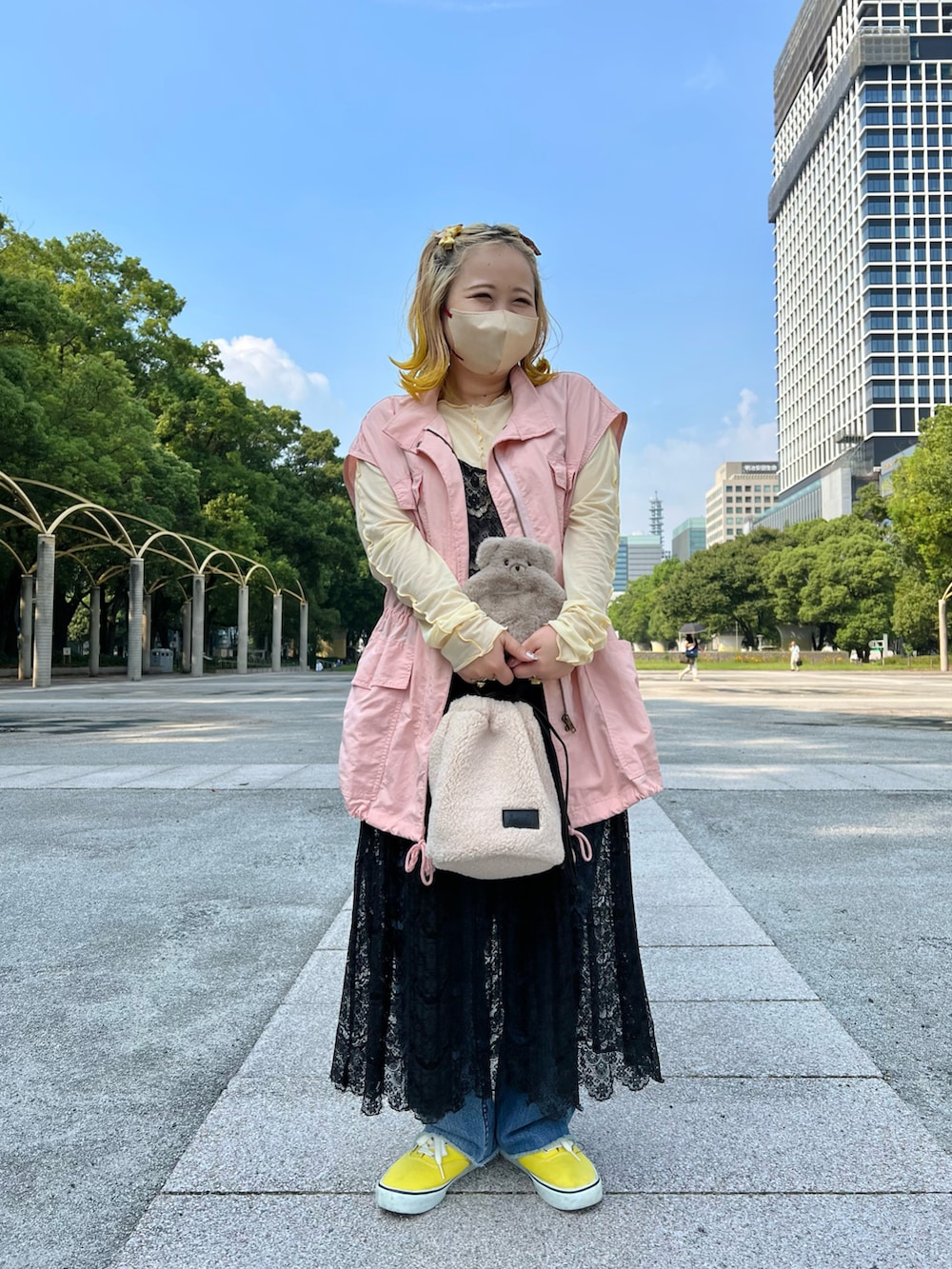 ホワイト系のショルダーバッグ、ピンク系のベスト、イエロー系のTシャツ/カットソーを着用したレディースの秋コーディネートの2枚目の写真