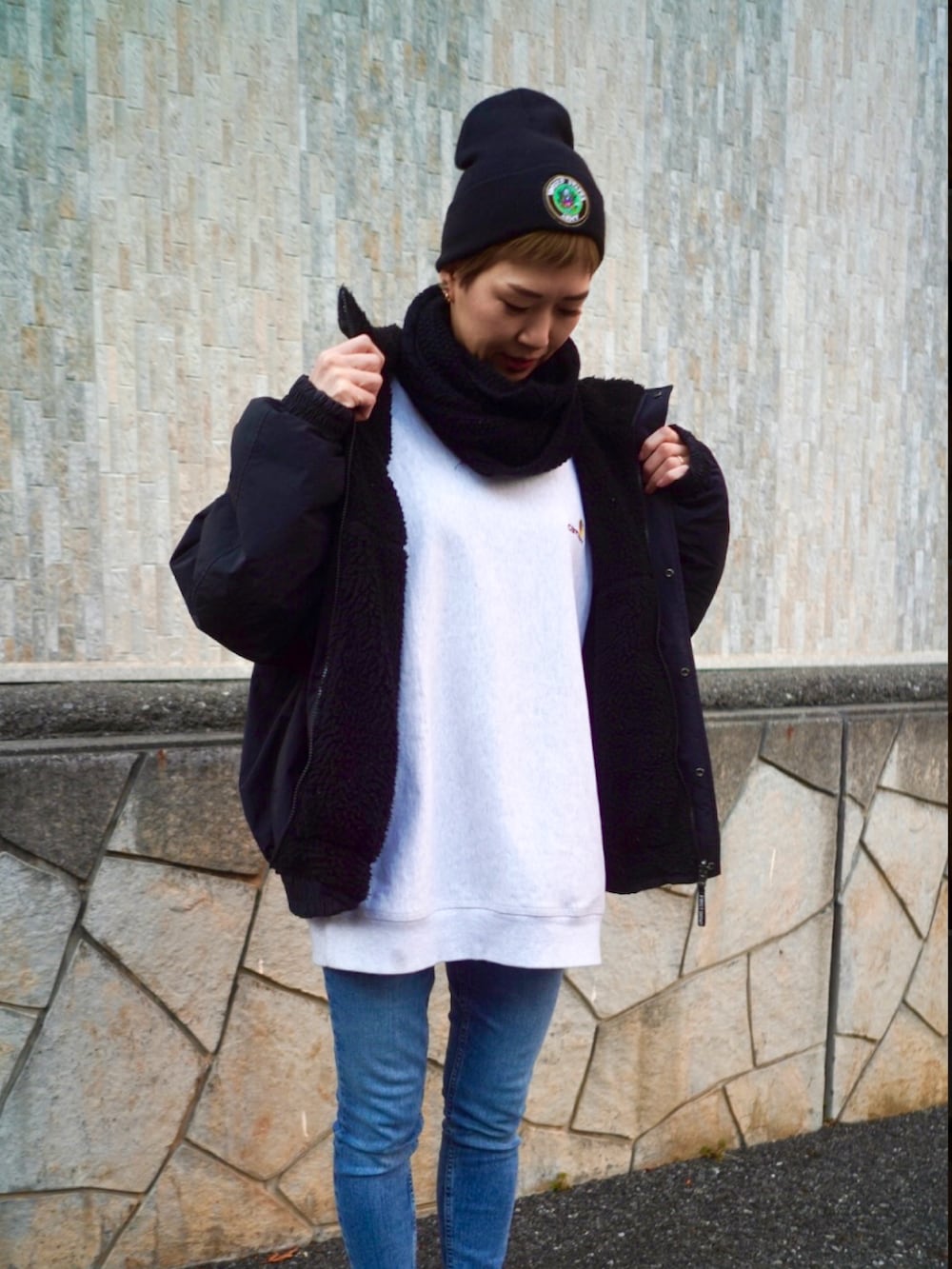 ブラック系のブルゾン、ホワイト系のスニーカー、ブルー系のデニムパンツを着用したレディースの冬コーディネートの3枚目の写真