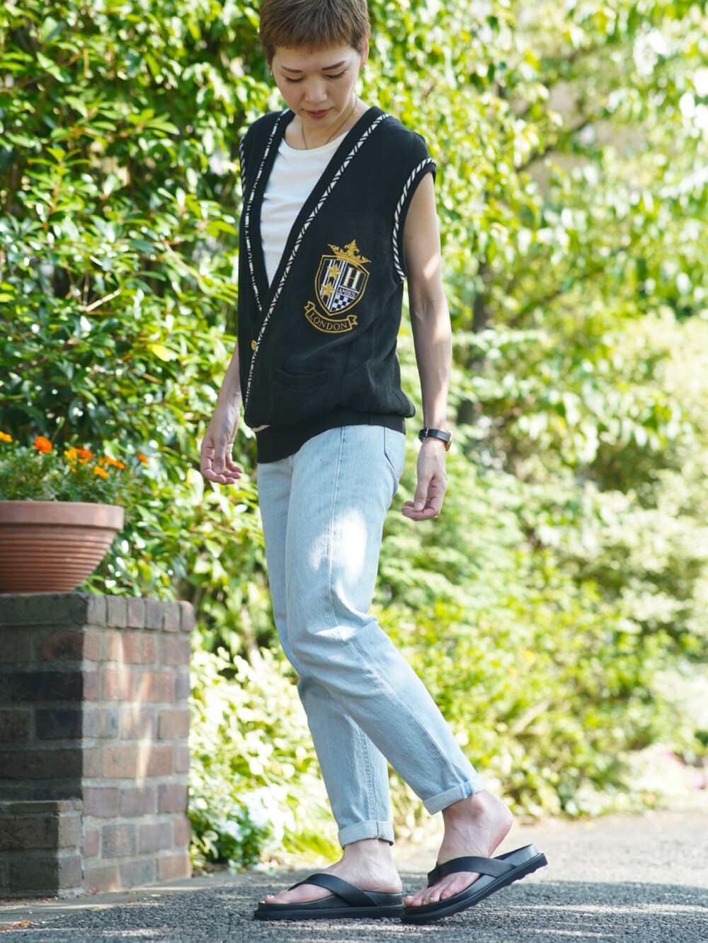 ブルー系のデニムパンツ、ブラック系のサンダル、ブラック系のベストを着用したレディースの夏コーディネートの2枚目の写真