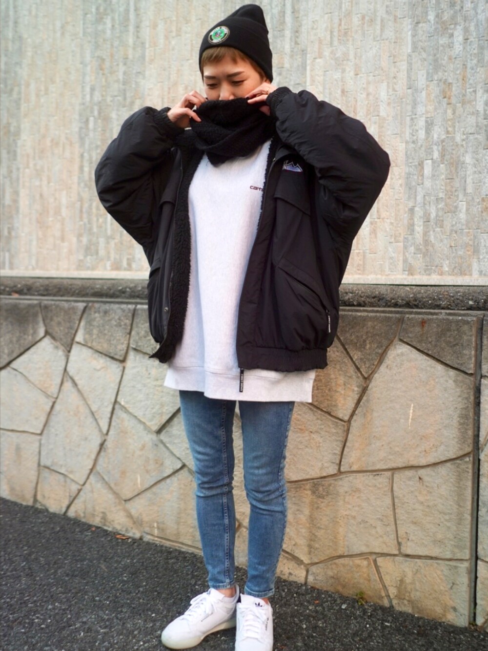 ブラック系のブルゾン、ホワイト系のスニーカー、ブルー系のデニムパンツを着用したレディースの冬コーディネートの2枚目の写真