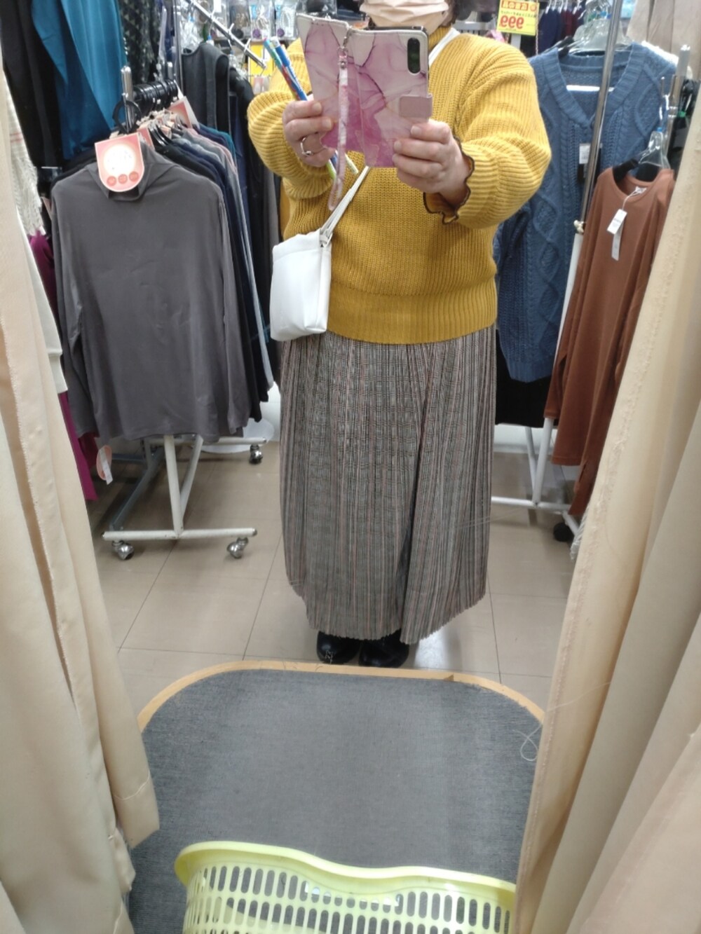 イエロー系のニット/セーター、グレー系のスカートを着用したレディースの秋コーディネートの2枚目の写真