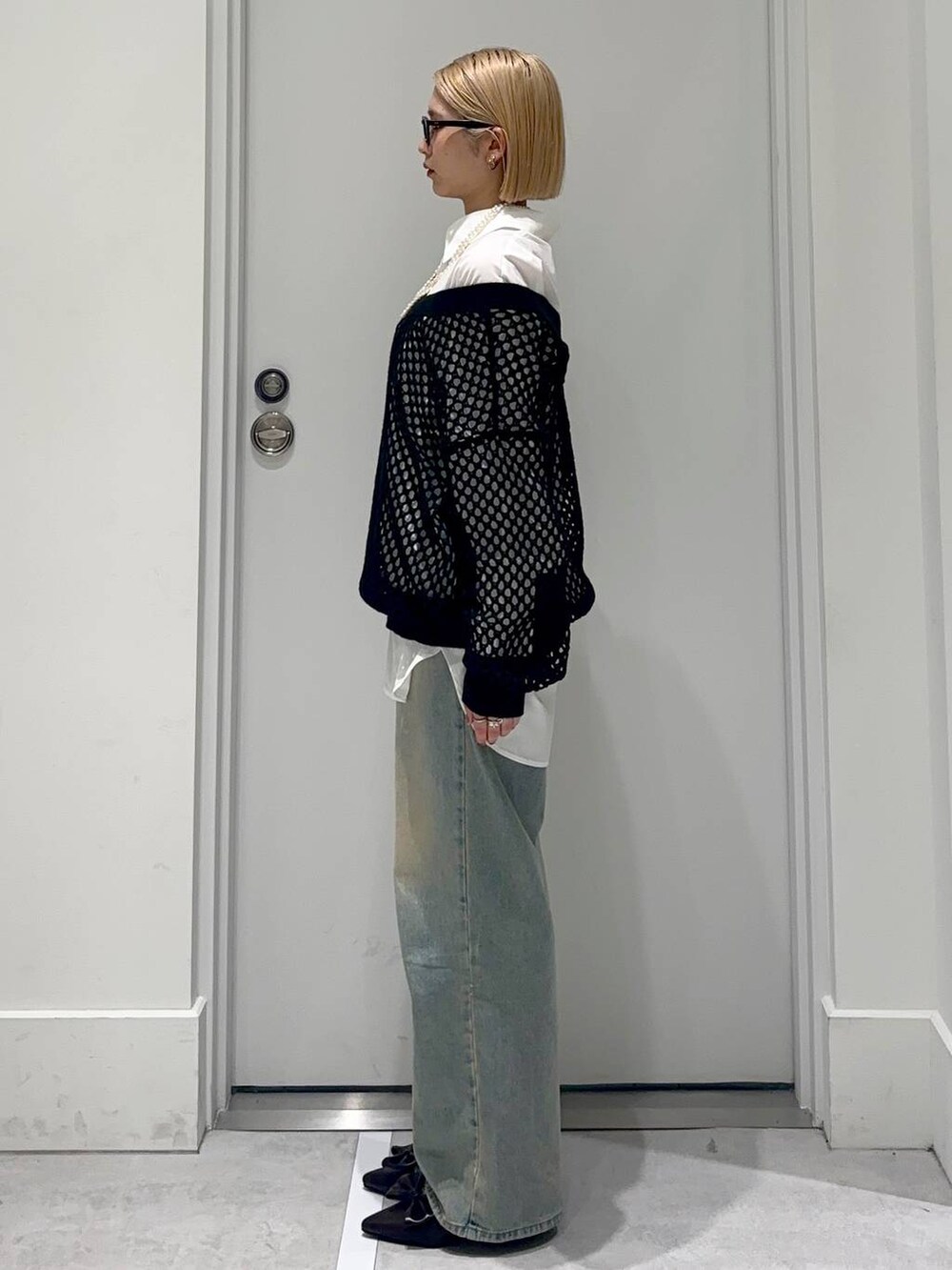 ブルー系のデニムパンツ、ブラック系のサンダル、ブラック系のニット/セーターを着用したレディースの春コーディネートの3枚目の写真