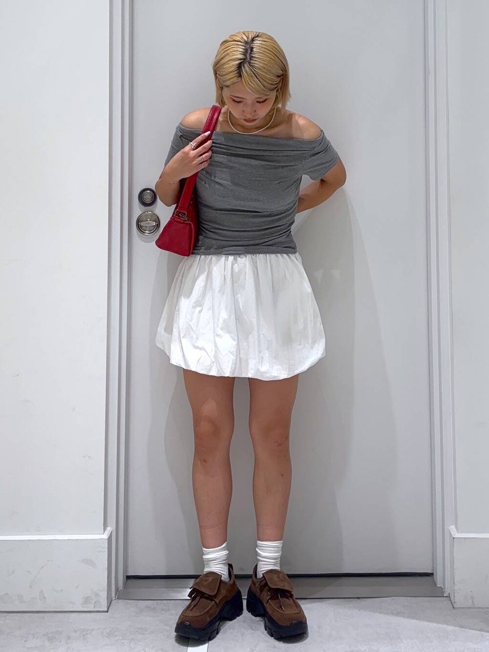 ホワイト系のスカート、グレー系のTシャツ/カットソー、ブラウン系のモカシン/デッキシューズを着用したレディースの夏コーディネートの4枚目の写真