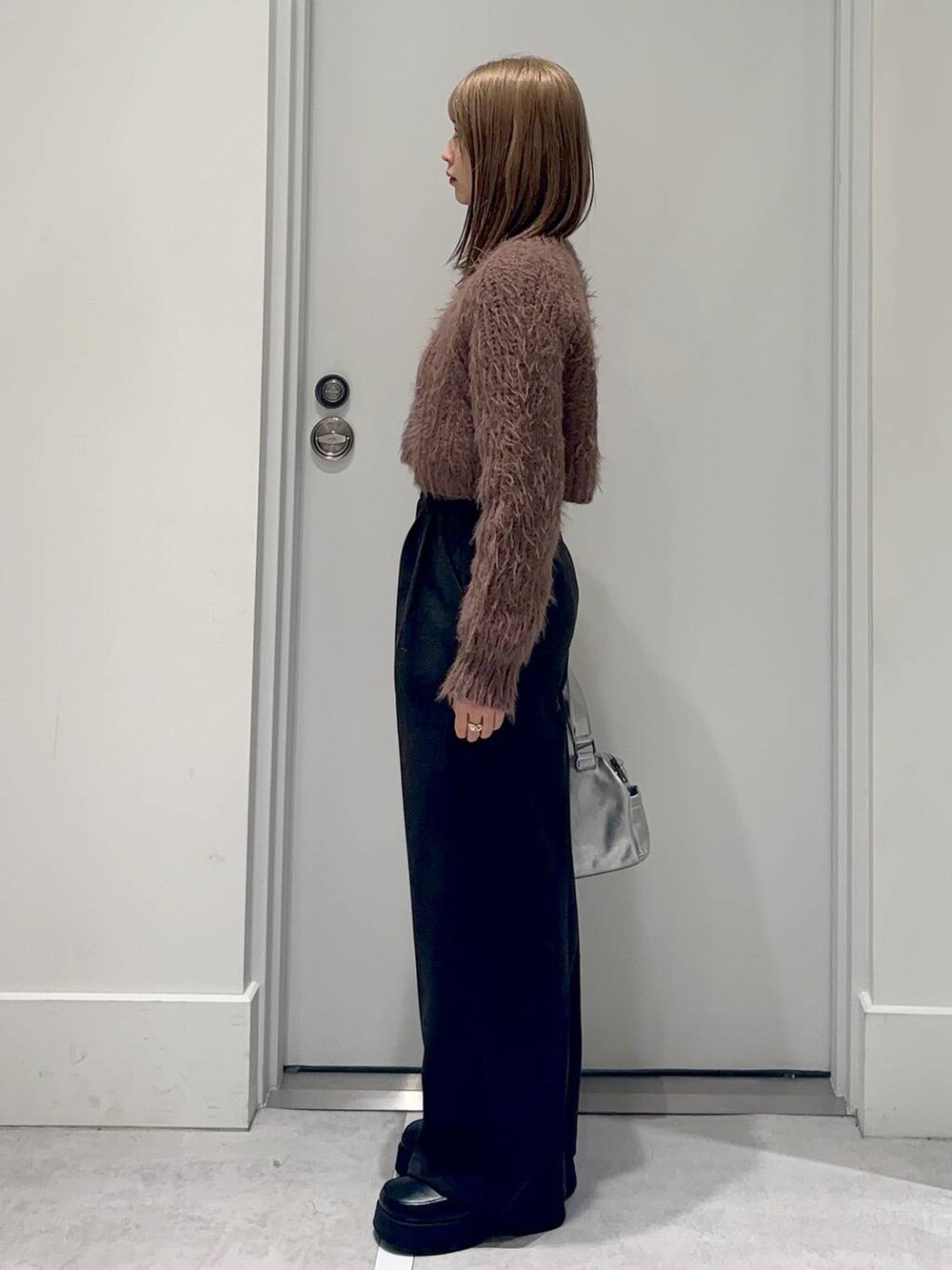 シルバー系のショルダーバッグ、ブラック系のスリッポン、ブラウン系のニット/セーターを着用したレディースの冬コーディネートの3枚目の写真