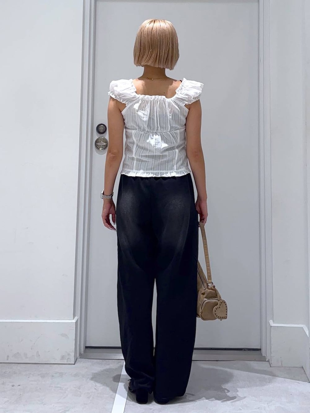 ブラック系のサンダル、ホワイト系のシャツ/ブラウス、ベージュ系のハンドバッグを着用したレディースの夏コーディネートの4枚目の写真