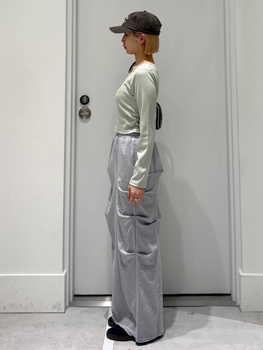 グレー系のスカート、グリーン系のTシャツ/カットソー、ブラウン系のボストンバッグを着用したレディースの春コーディネートの4枚目の写真