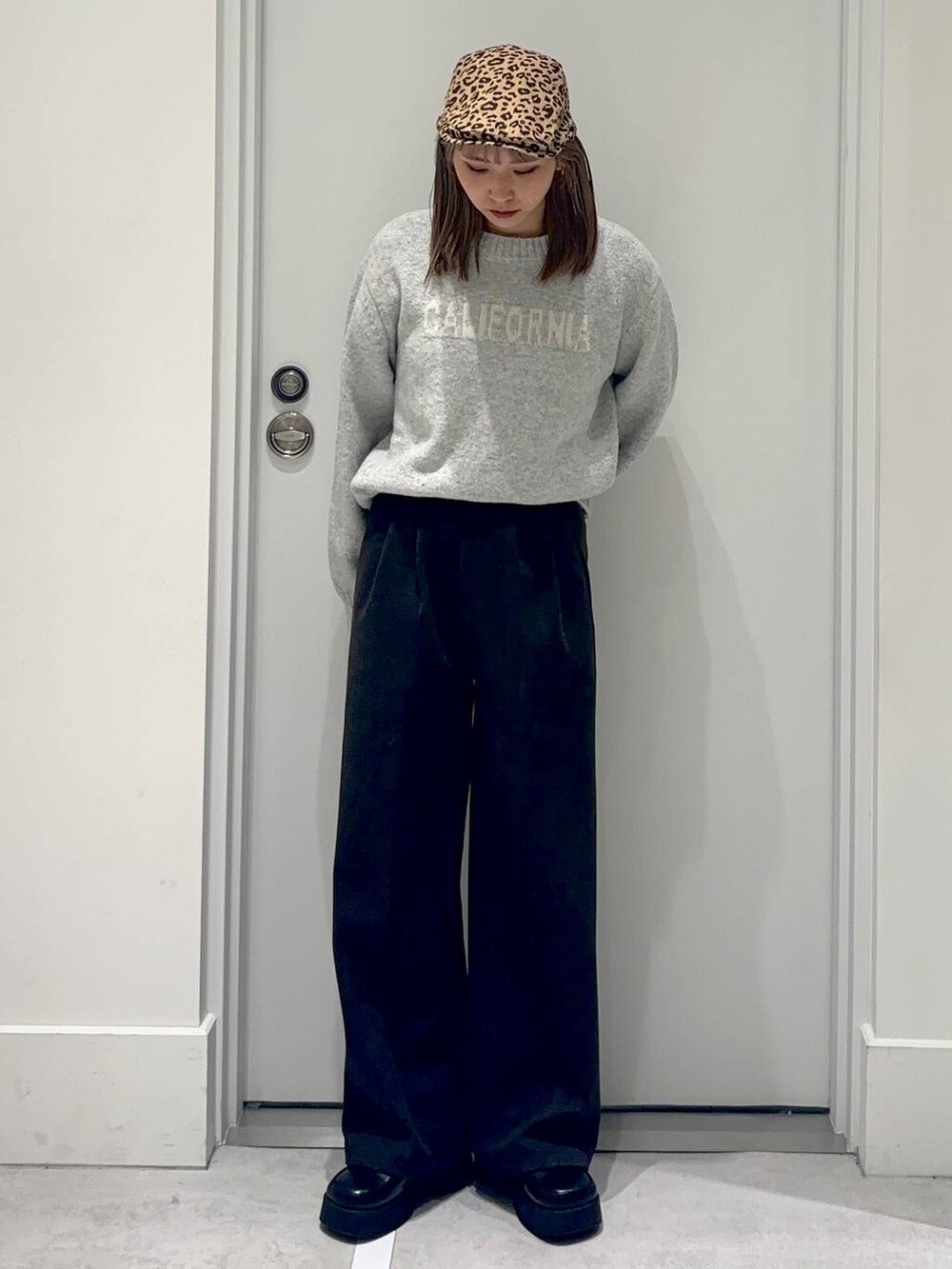 ブラック系のスリッポン、グレー系のスラックス、グレー系のニット/セーターを着用したレディースの冬コーディネートの2枚目の写真