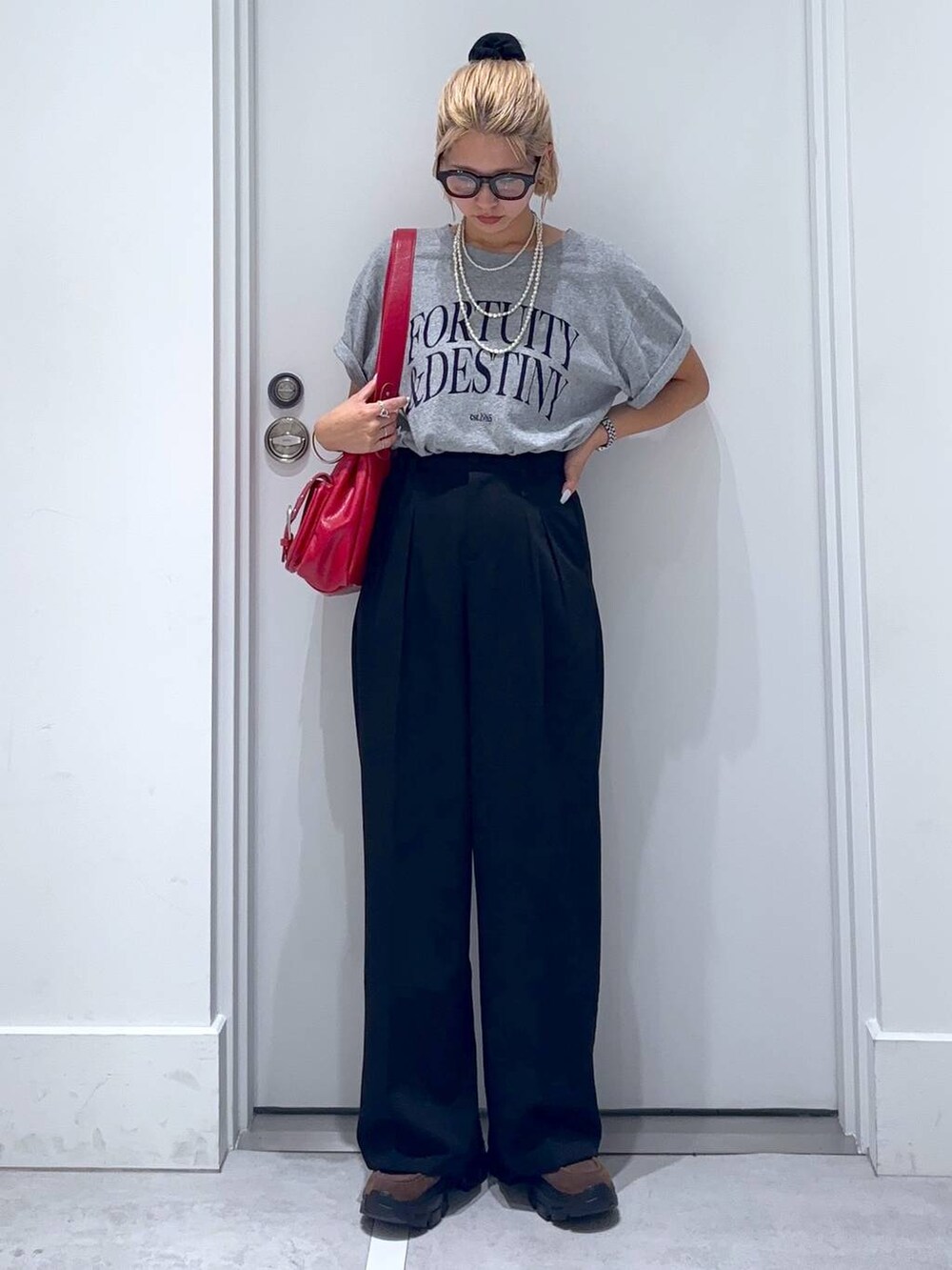 ブラウン系のモカシン/デッキシューズ、グレー系のTシャツ/カットソー、ブラック系のスラックスを着用したレディースの夏コーディネートの2枚目の写真
