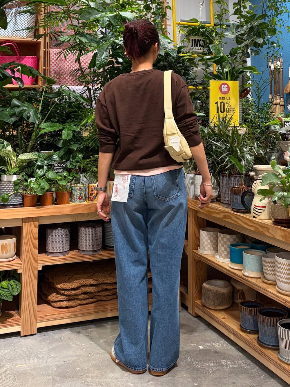 ブルー系のデニムパンツ、ブラウン系のニット/セーター、ブラック系のショルダーバッグを着用したレディースの秋コーディネートの5枚目の写真