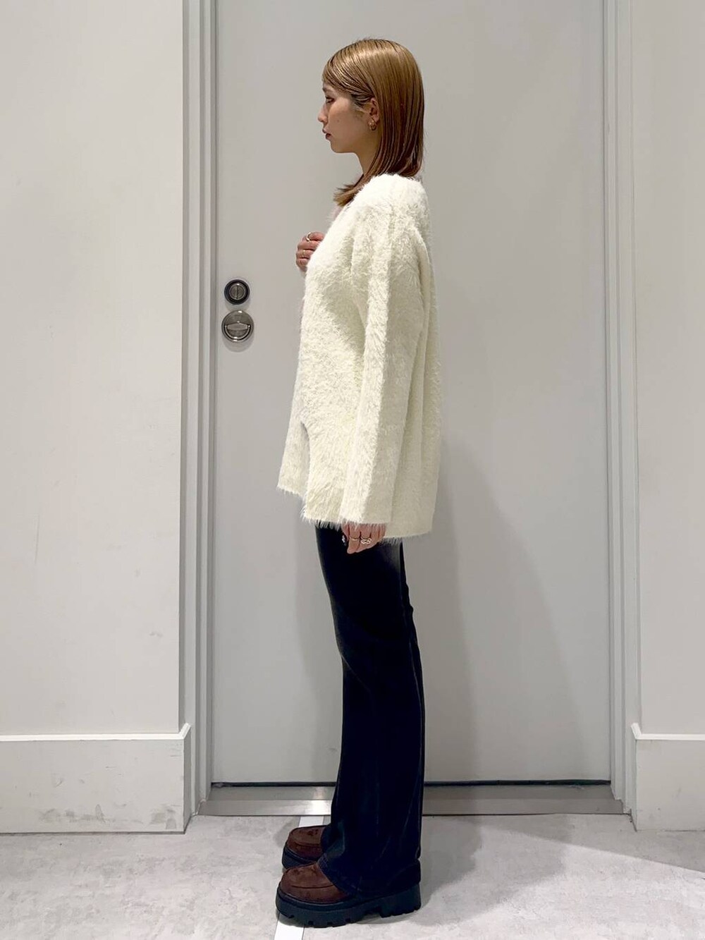ブラウン系のローファー、ブラック系のデニムパンツ、ベージュ系のチュニックを着用したレディースの冬コーディネートの2枚目の写真