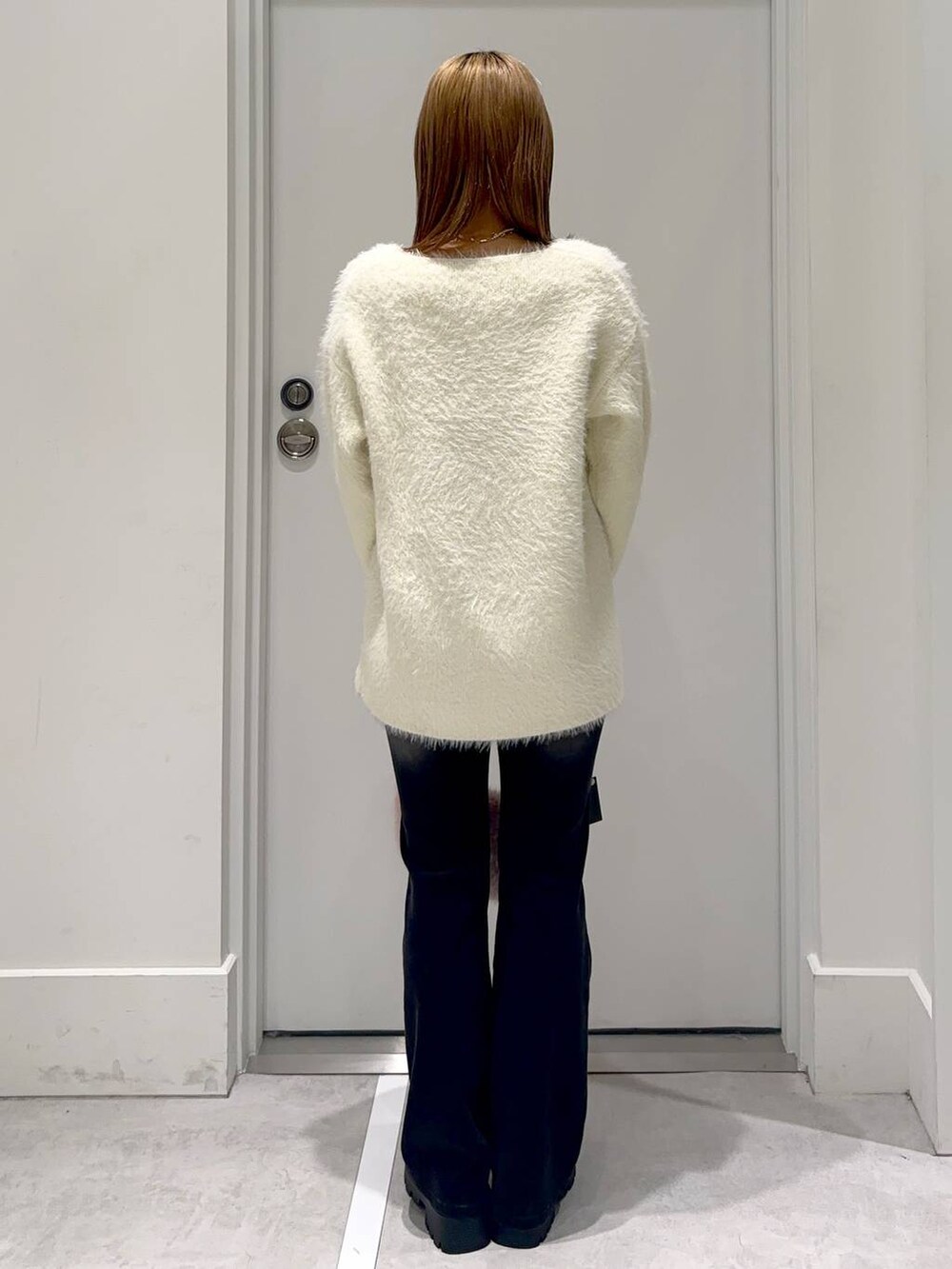ブラウン系のローファー、ブラック系のデニムパンツ、ベージュ系のチュニックを着用したレディースの冬コーディネートの4枚目の写真
