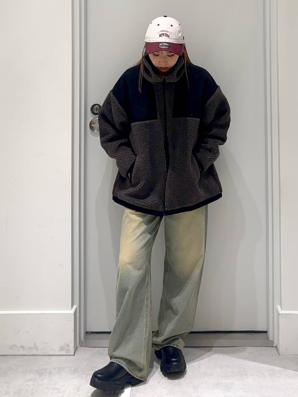 グレー系のブルゾン、ブルー系のデニムパンツ、ブラック系のブーツを着用したレディースの冬コーディネートの2枚目の写真