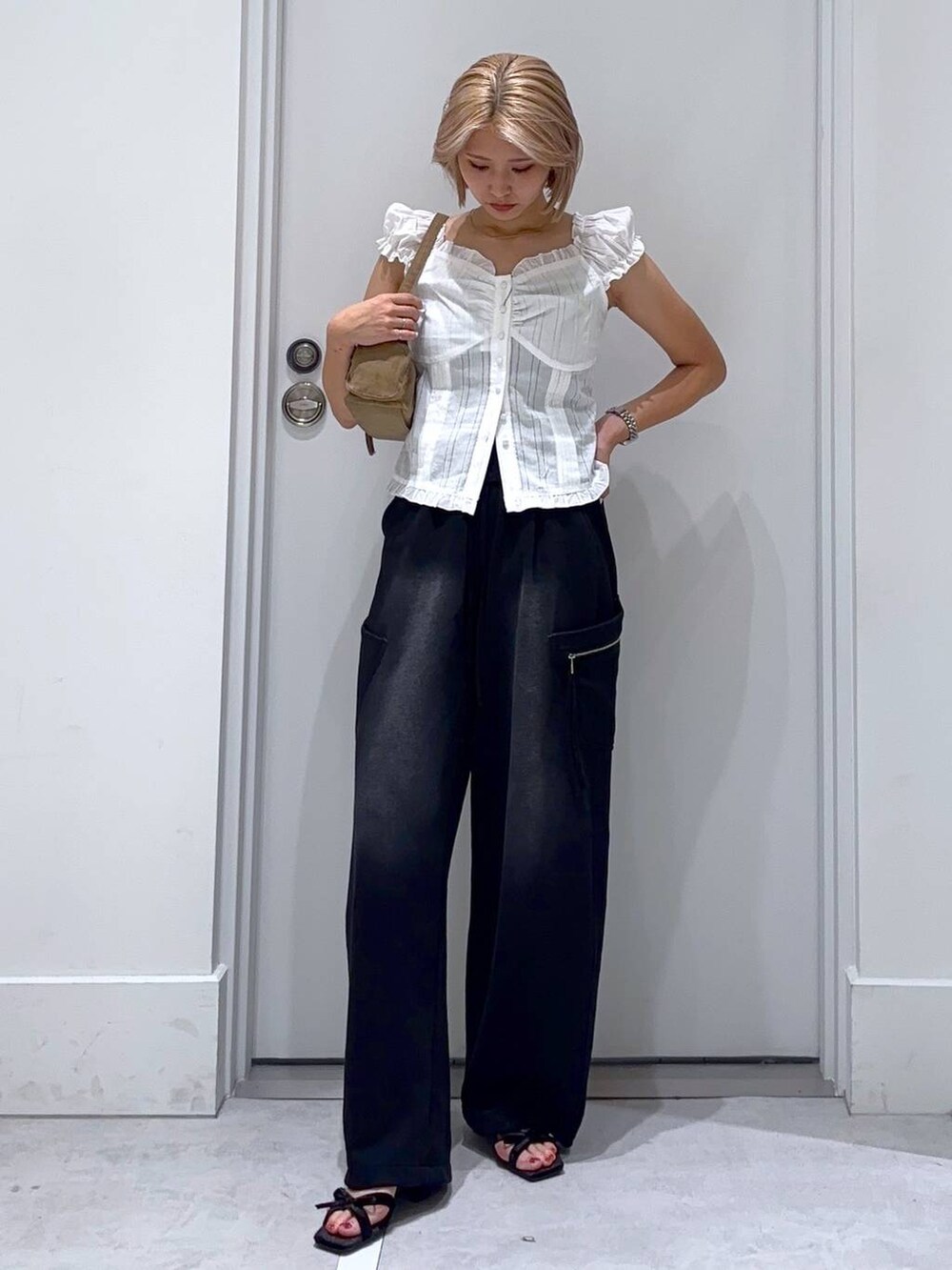 ブラック系のサンダル、ホワイト系のシャツ/ブラウス、ベージュ系のハンドバッグを着用したレディースの夏コーディネートの2枚目の写真