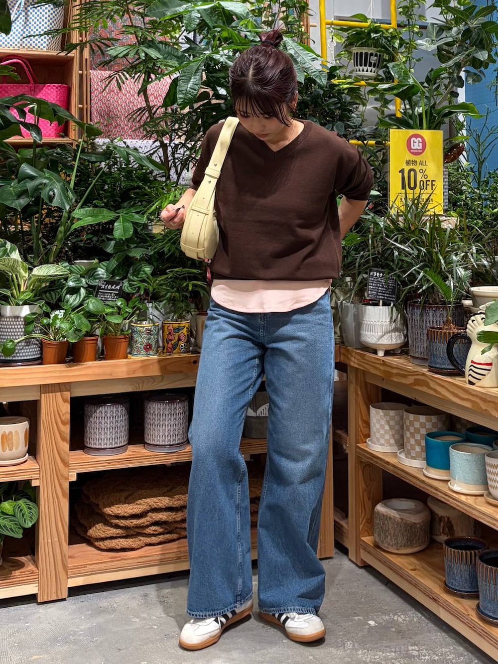 ブルー系のデニムパンツ、ブラウン系のニット/セーター、ブラック系のショルダーバッグを着用したレディースの秋コーディネートの2枚目の写真