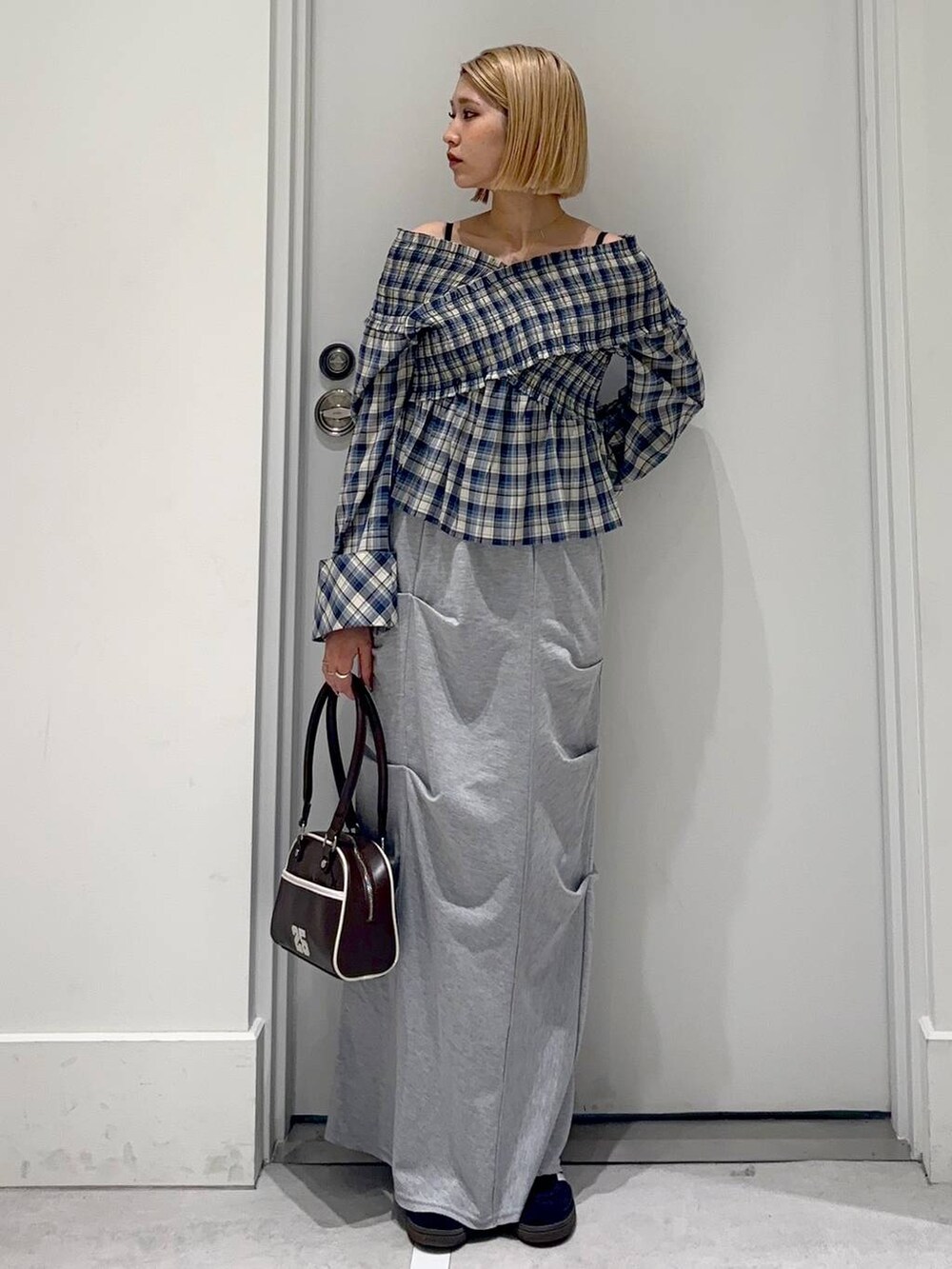 グレー系のスカート、ブラック系のシャツ/ブラウス、レッド系のボストンバッグを着用したレディースの春コーディネートの2枚目の写真