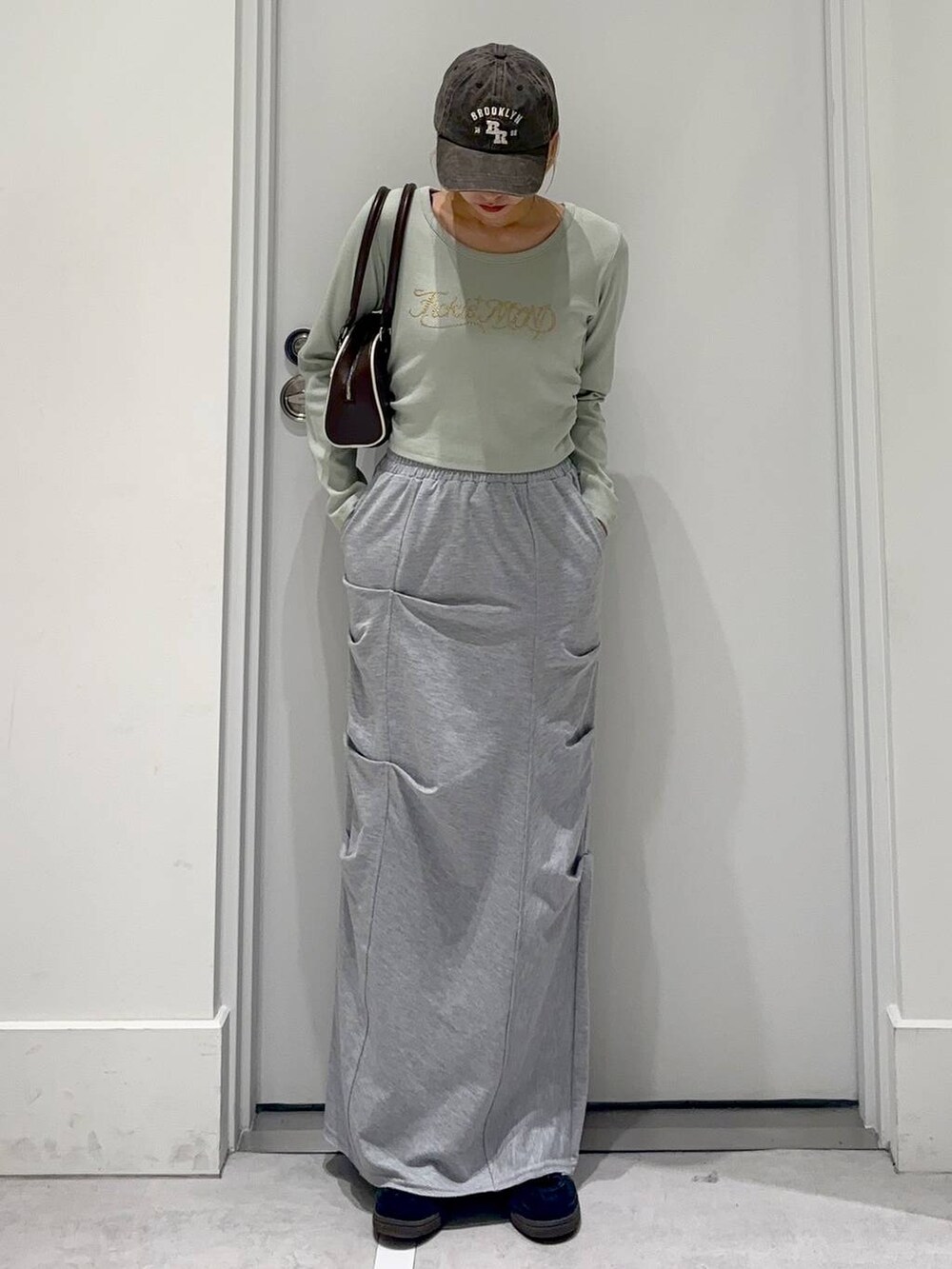グレー系のスカート、グリーン系のTシャツ/カットソー、ブラウン系のボストンバッグを着用したレディースの春コーディネートの3枚目の写真