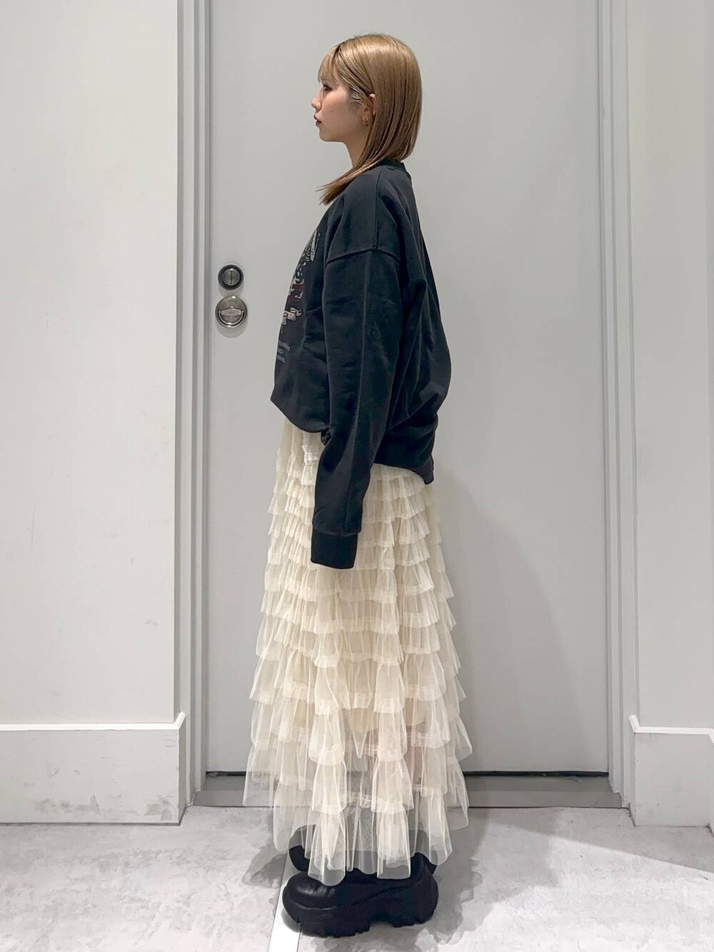 グレー系のスウェット、ブラック系のブーツ、ホワイト系のスカートを着用したレディースの冬コーディネートの3枚目の写真