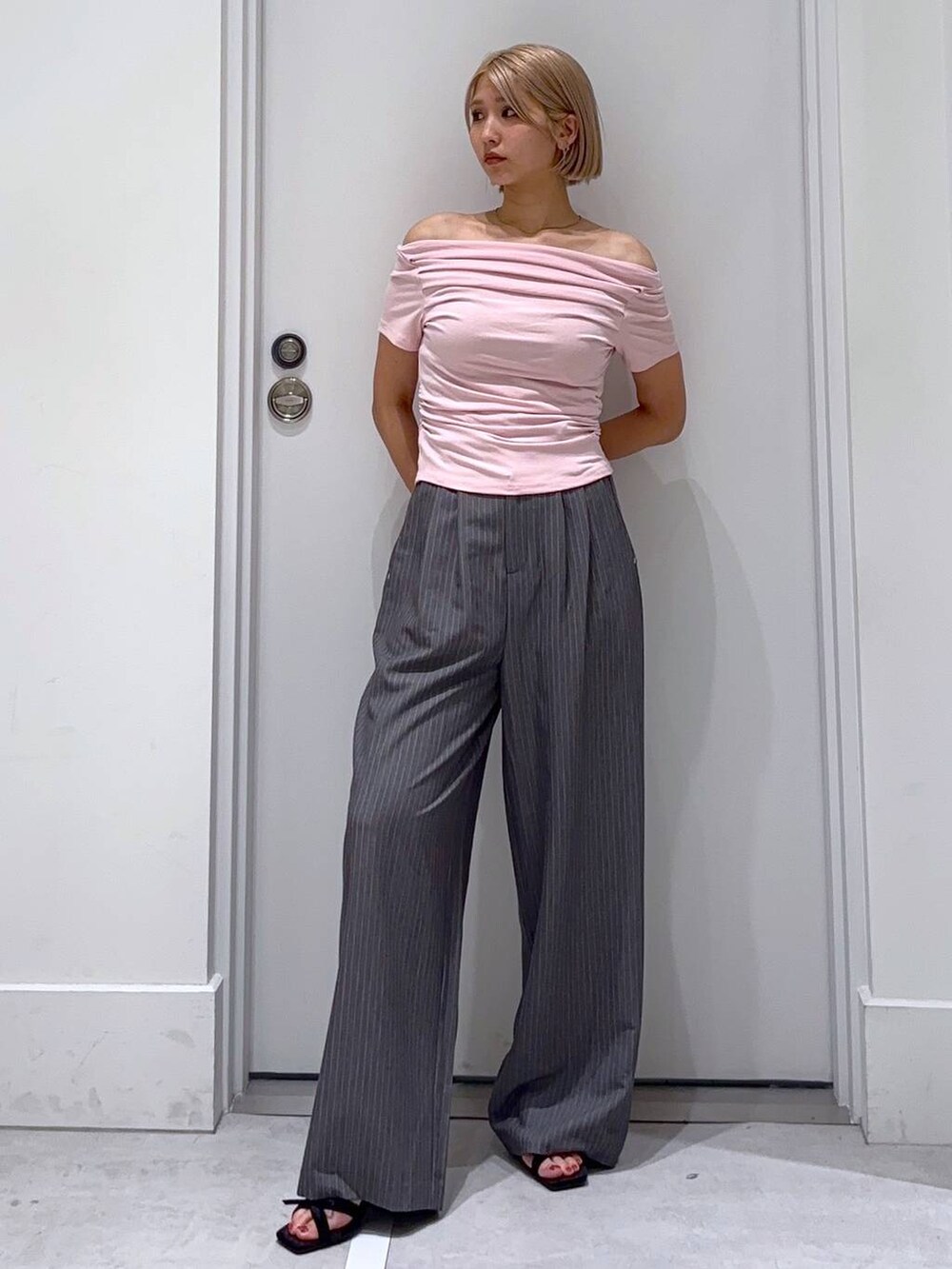 ブラック系のサンダル、グレー系のスラックスを着用したレディースの夏コーディネートの2枚目の写真