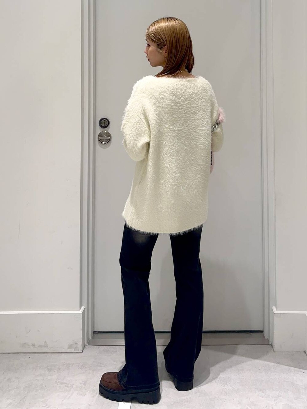 ブラウン系のローファー、ブラック系のデニムパンツ、ベージュ系のチュニックを着用したレディースの冬コーディネートの3枚目の写真