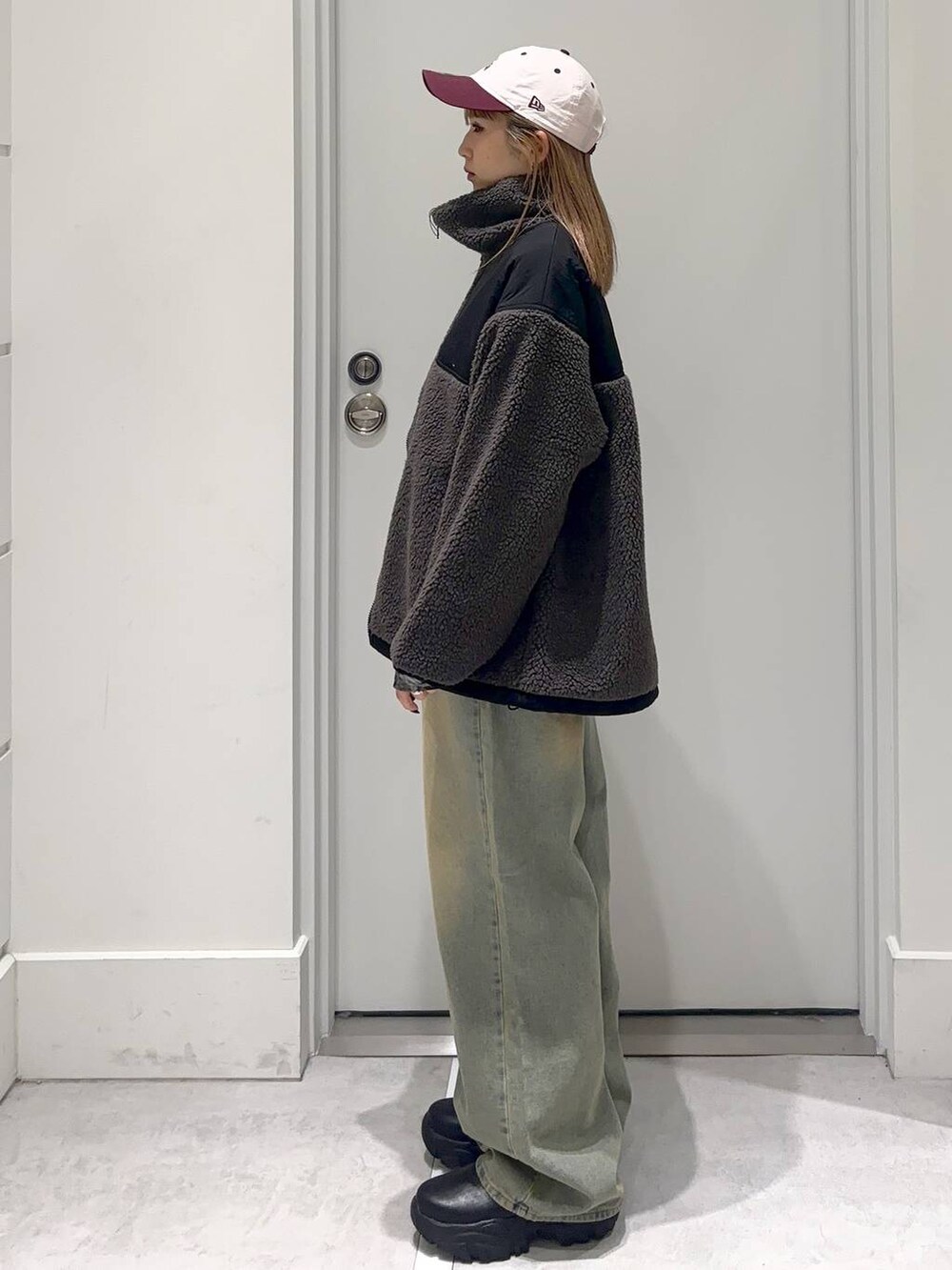 グレー系のブルゾン、ブルー系のデニムパンツ、ブラック系のブーツを着用したレディースの冬コーディネートの3枚目の写真