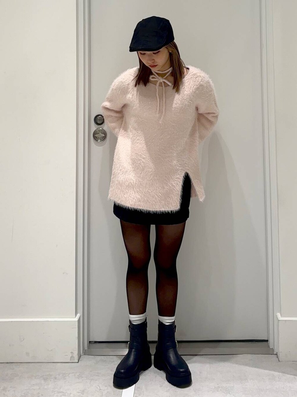 ブラック系のスカート、ピンク系のチュニック、ブラック系のハンチング/ベレー帽を着用したレディースの冬コーディネートの2枚目の写真