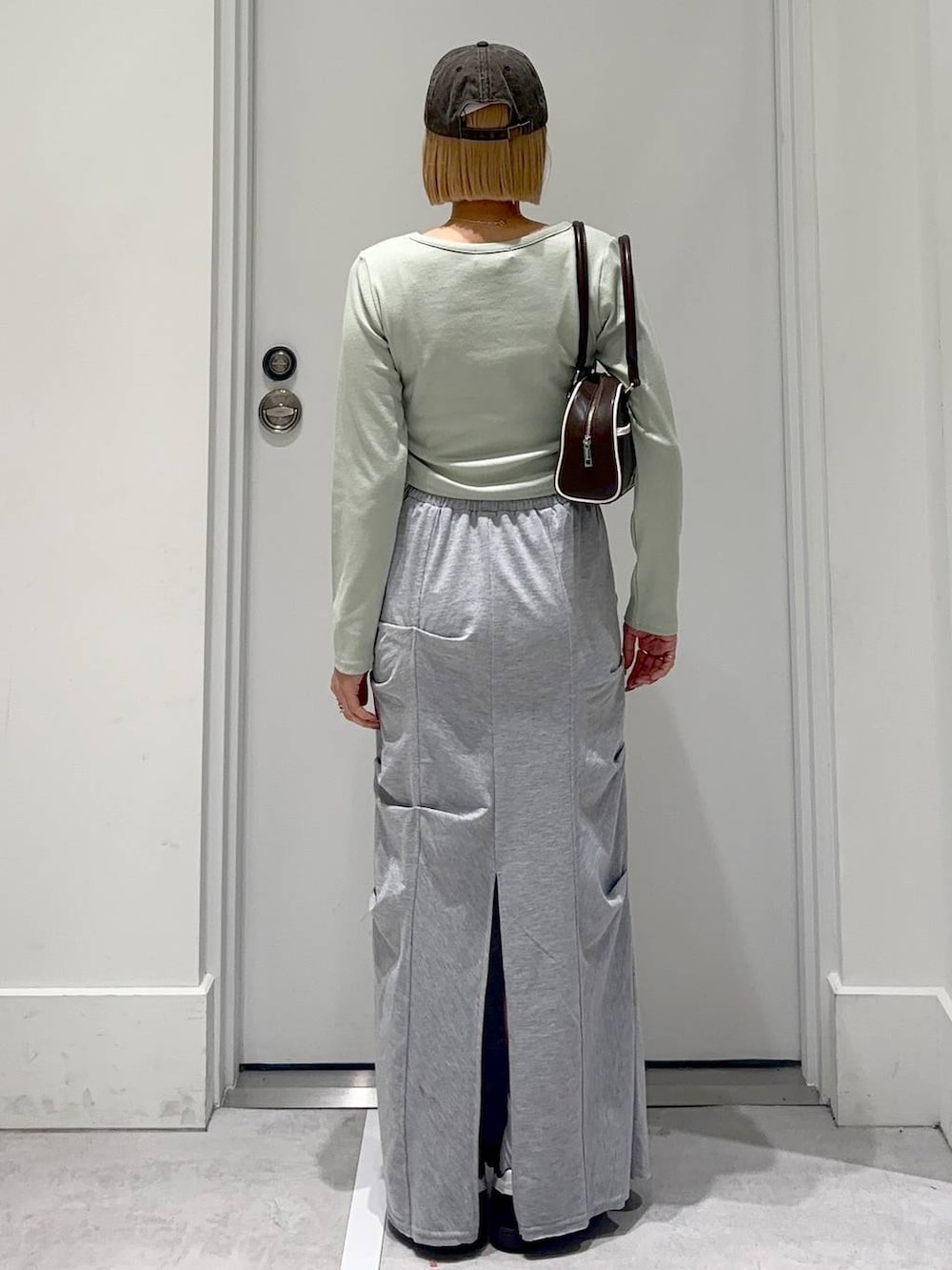 グレー系のスカート、グリーン系のTシャツ/カットソー、ブラウン系のボストンバッグを着用したレディースの春コーディネートの5枚目の写真