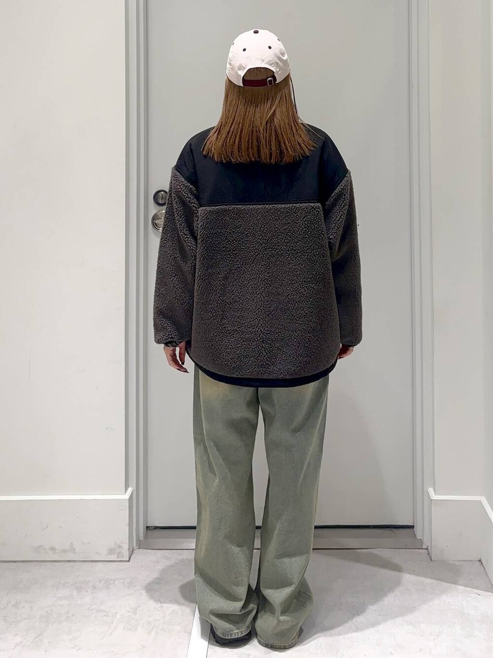 グレー系のブルゾン、ブルー系のデニムパンツ、ブラック系のブーツを着用したレディースの冬コーディネートの4枚目の写真