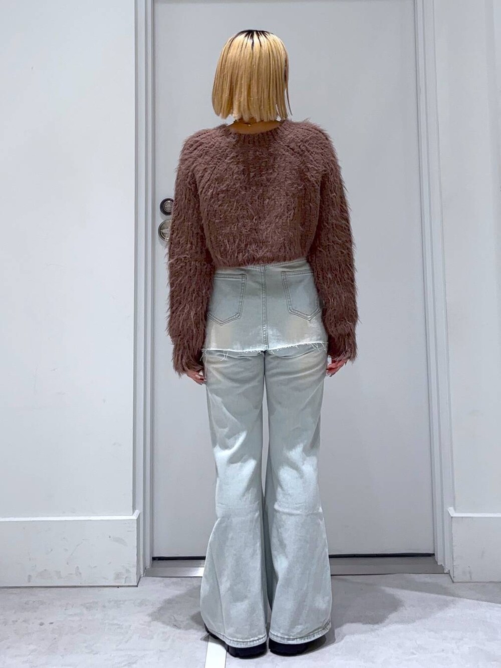 ブラウン系のニット/セーター、ブラック系のモカシン/デッキシューズ、ブルー系のデニムパンツを着用したレディースの秋コーディネートの5枚目の写真