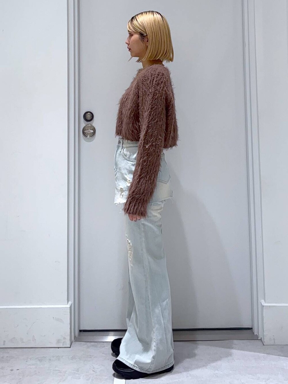 ブラウン系のニット/セーター、ブラック系のモカシン/デッキシューズ、ブルー系のデニムパンツを着用したレディースの秋コーディネートの4枚目の写真