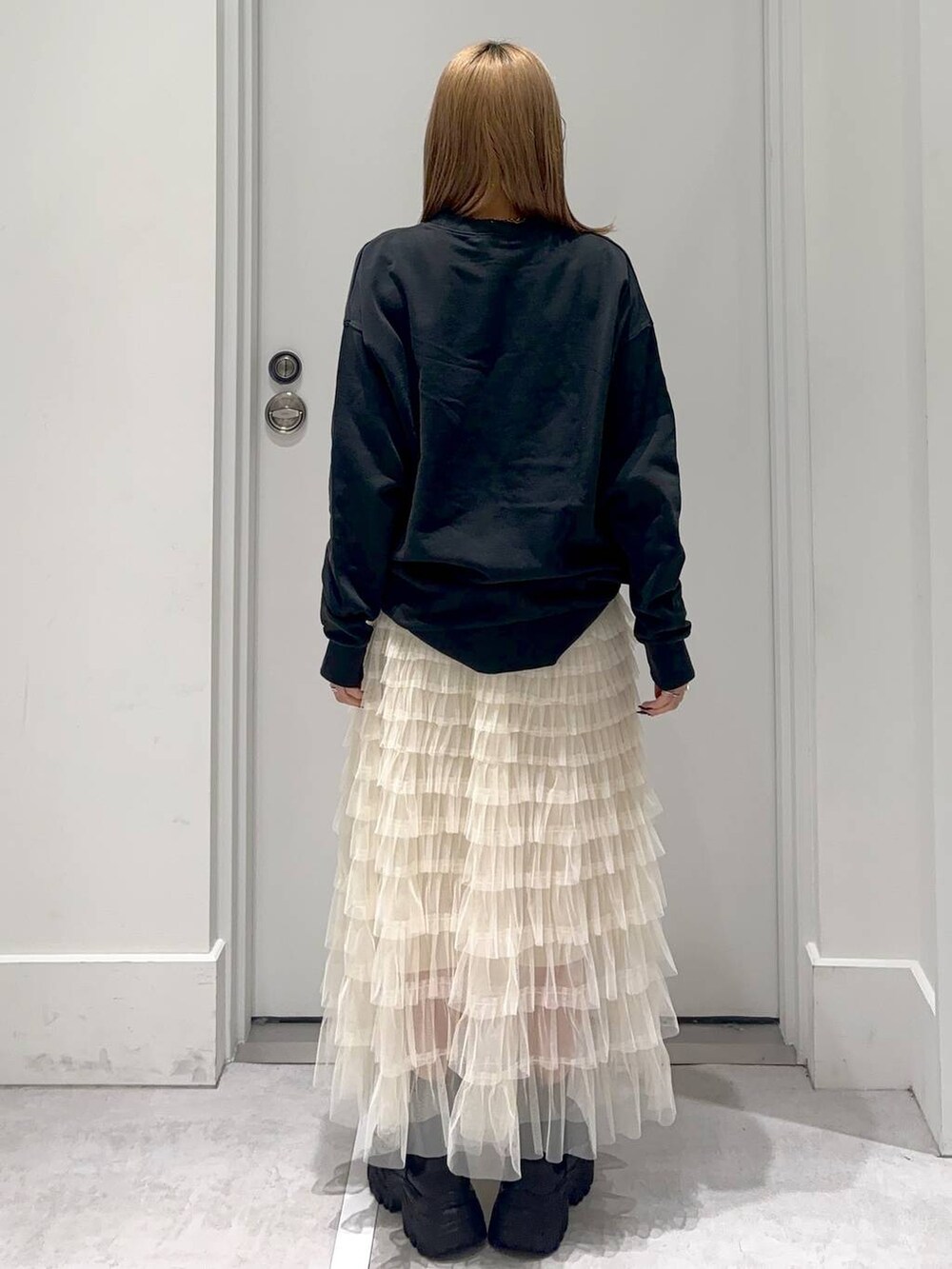 グレー系のスウェット、ブラック系のブーツ、ホワイト系のスカートを着用したレディースの冬コーディネートの4枚目の写真