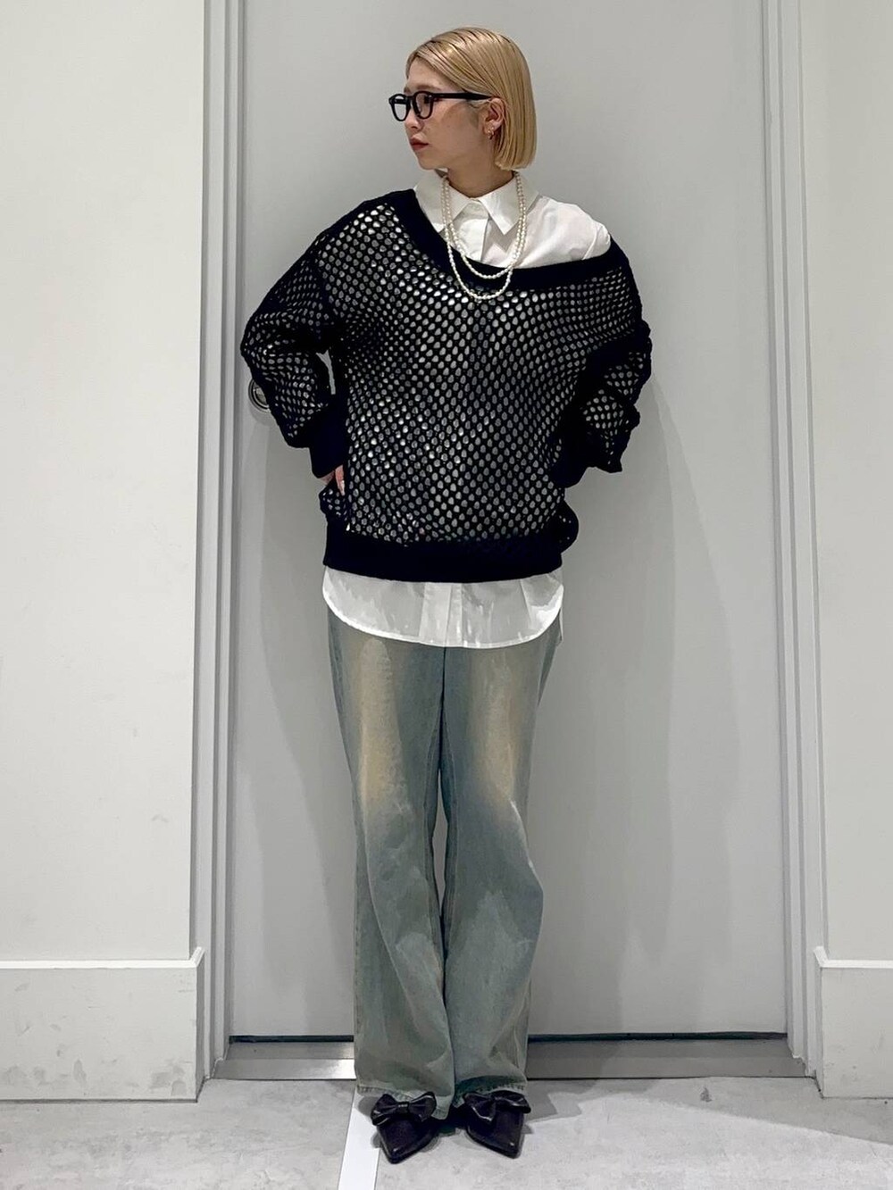 ブルー系のデニムパンツ、ブラック系のサンダル、ブラック系のニット/セーターを着用したレディースの春コーディネートの2枚目の写真