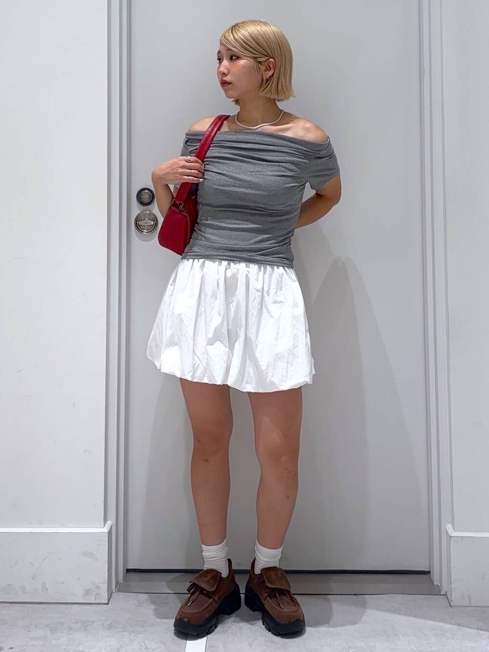 ホワイト系のスカート、グレー系のTシャツ/カットソー、ブラウン系のモカシン/デッキシューズを着用したレディースの夏コーディネートの3枚目の写真