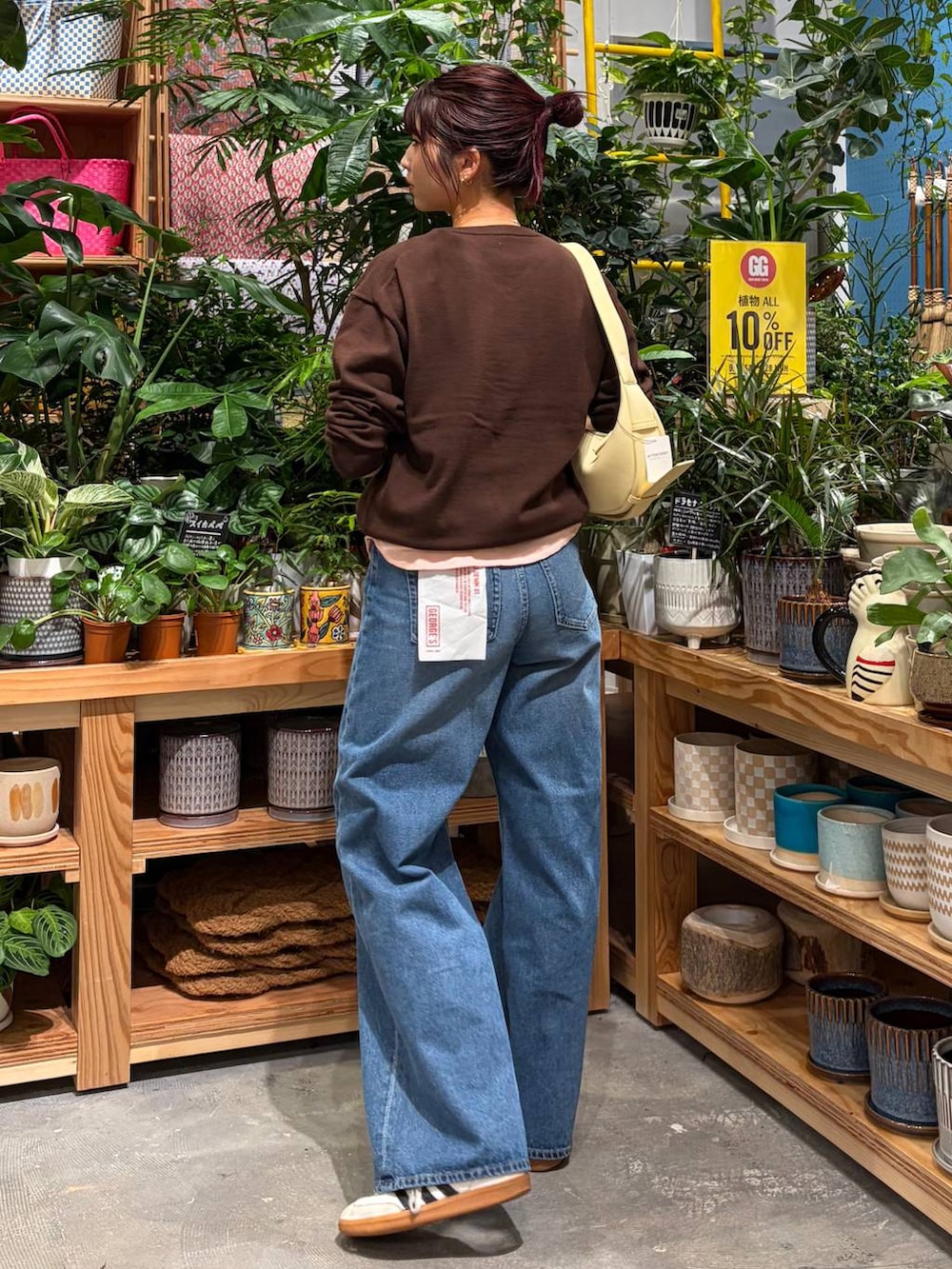 ブルー系のデニムパンツ、ブラウン系のニット/セーター、ブラック系のショルダーバッグを着用したレディースの秋コーディネートの4枚目の写真