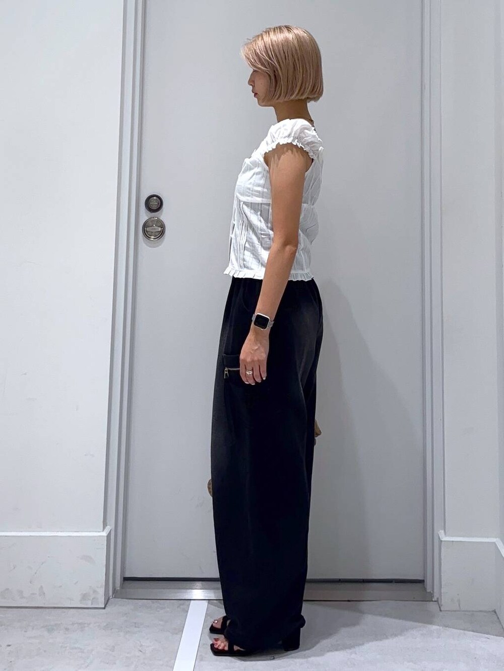 ブラック系のサンダル、ホワイト系のシャツ/ブラウス、ベージュ系のハンドバッグを着用したレディースの夏コーディネートの3枚目の写真