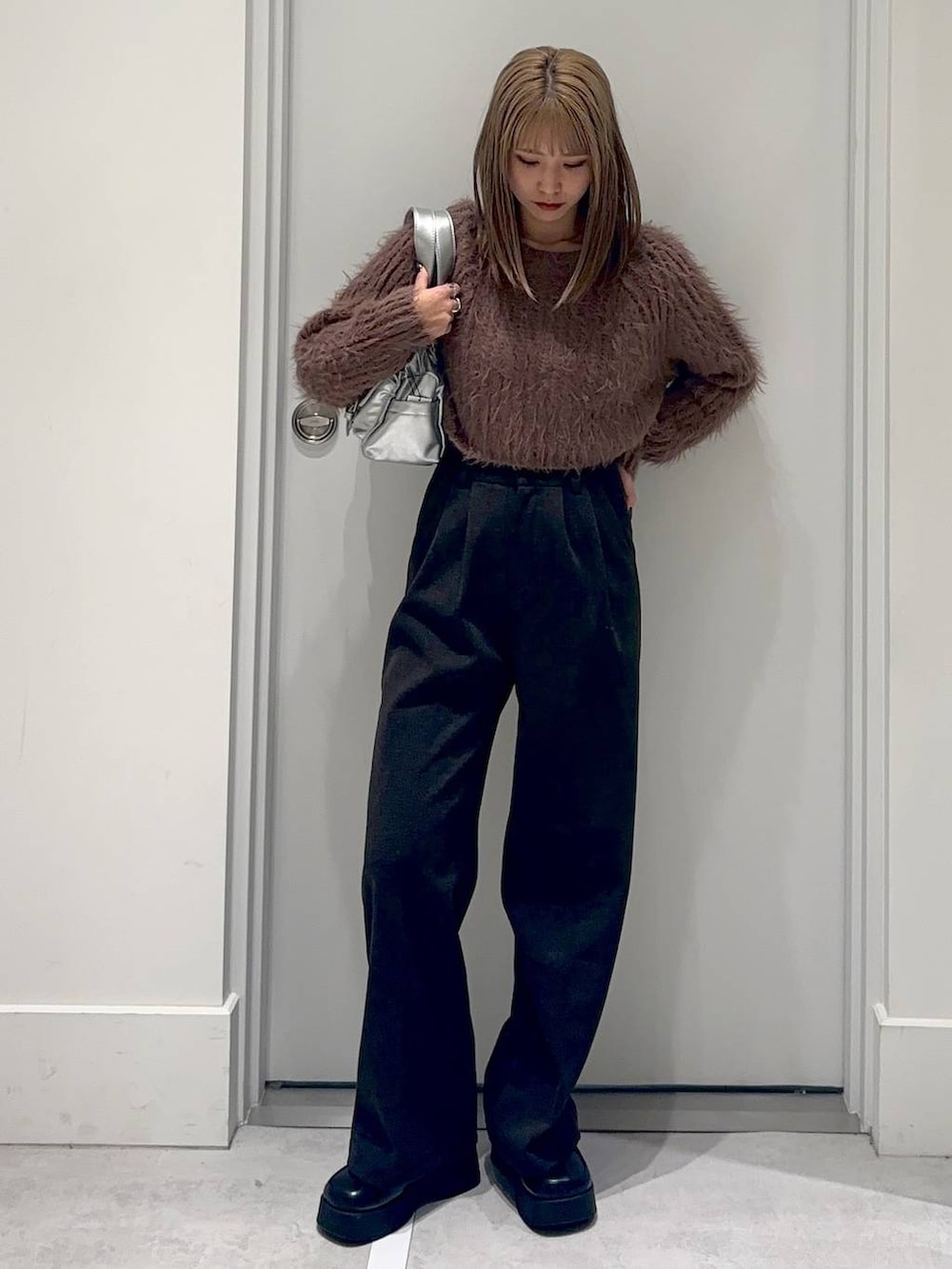 シルバー系のショルダーバッグ、ブラック系のスリッポン、ブラウン系のニット/セーターを着用したレディースの冬コーディネートの2枚目の写真