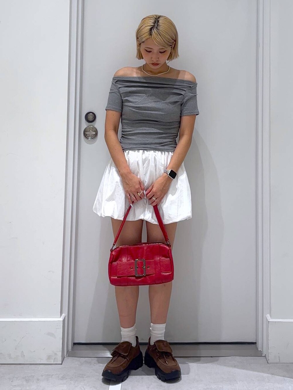 ホワイト系のスカート、グレー系のTシャツ/カットソー、ブラウン系のモカシン/デッキシューズを着用したレディースの夏コーディネートの2枚目の写真