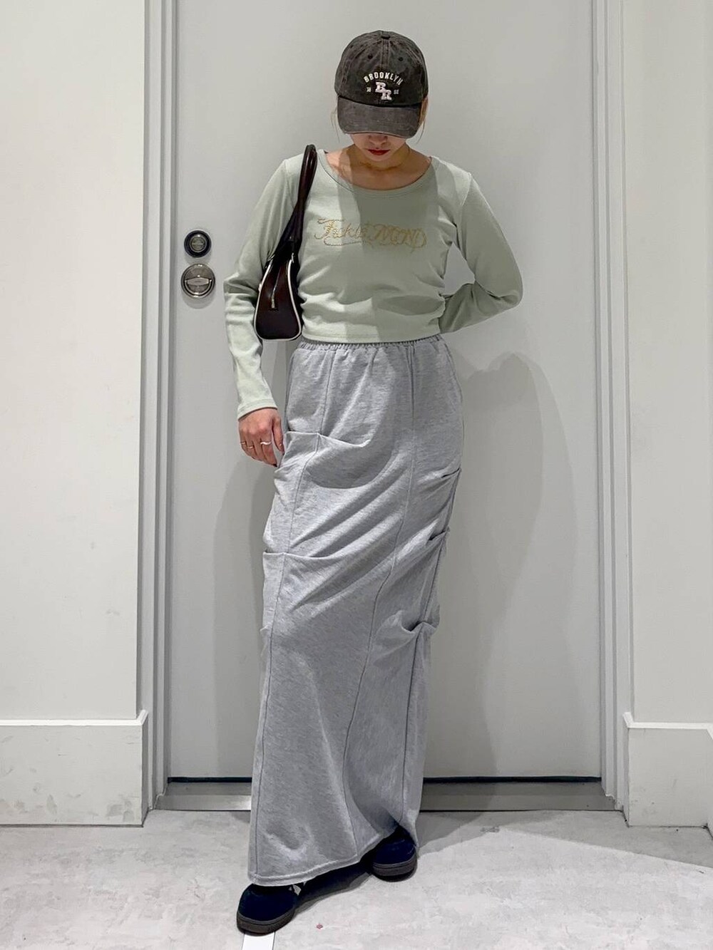 グレー系のスカート、グリーン系のTシャツ/カットソー、ブラウン系のボストンバッグを着用したレディースの春コーディネートの2枚目の写真