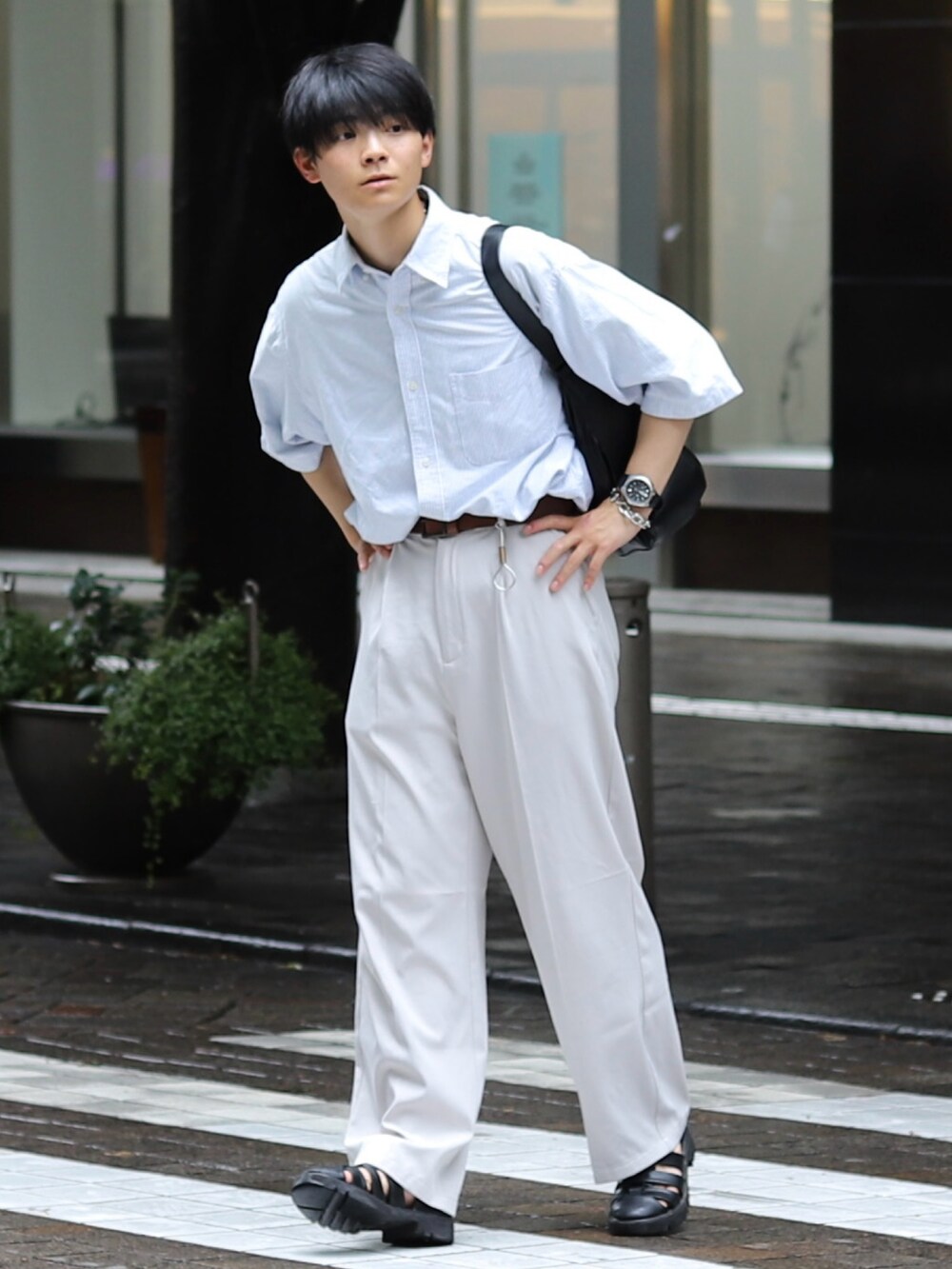 ホワイト系のスラックス、ブラック系のサンダル、ブラック系のバッグを着用したメンズの夏コーディネートの2枚目の写真