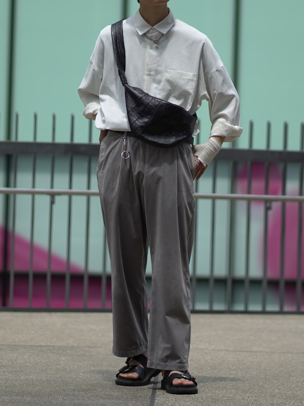 ブラック系のサンダル、グレー系のスラックス、ブラック系のバッグを着用したメンズの夏コーディネートの2枚目の写真