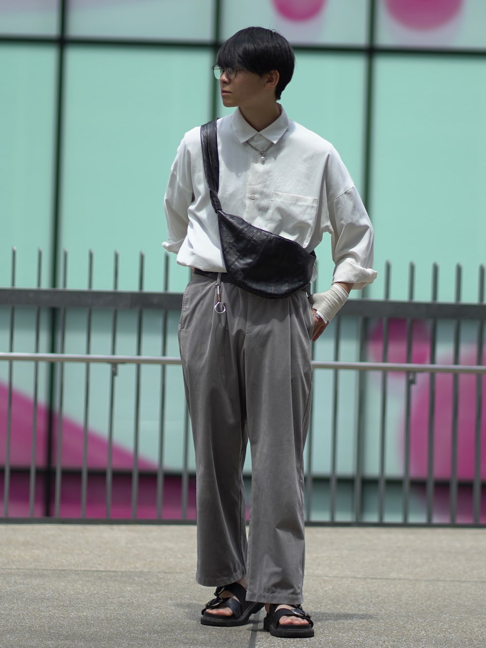 ブラック系のサンダル、グレー系のスラックス、ブラック系のバッグを着用したメンズの夏コーディネートの3枚目の写真