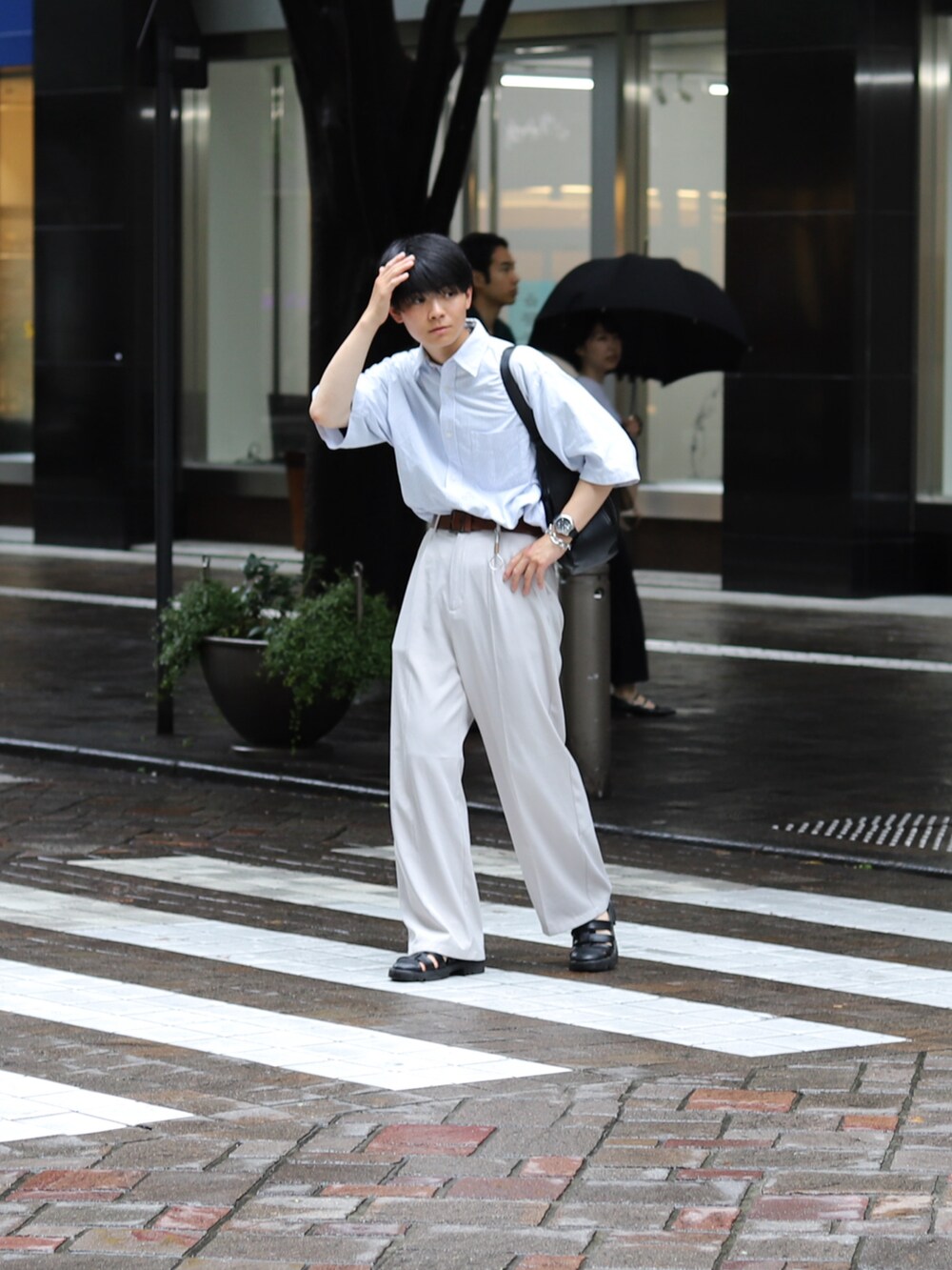 ホワイト系のスラックス、ブラック系のサンダル、ブラック系のバッグを着用したメンズの夏コーディネートの3枚目の写真