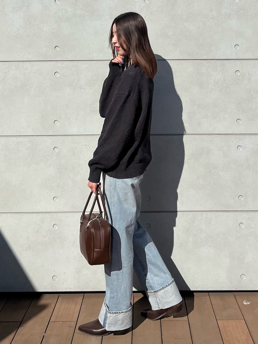 グレー系のニット/セーター、ブルー系のデニムパンツ、ブラウン系のハンドバッグを着用したレディースの冬コーディネートの2枚目の写真