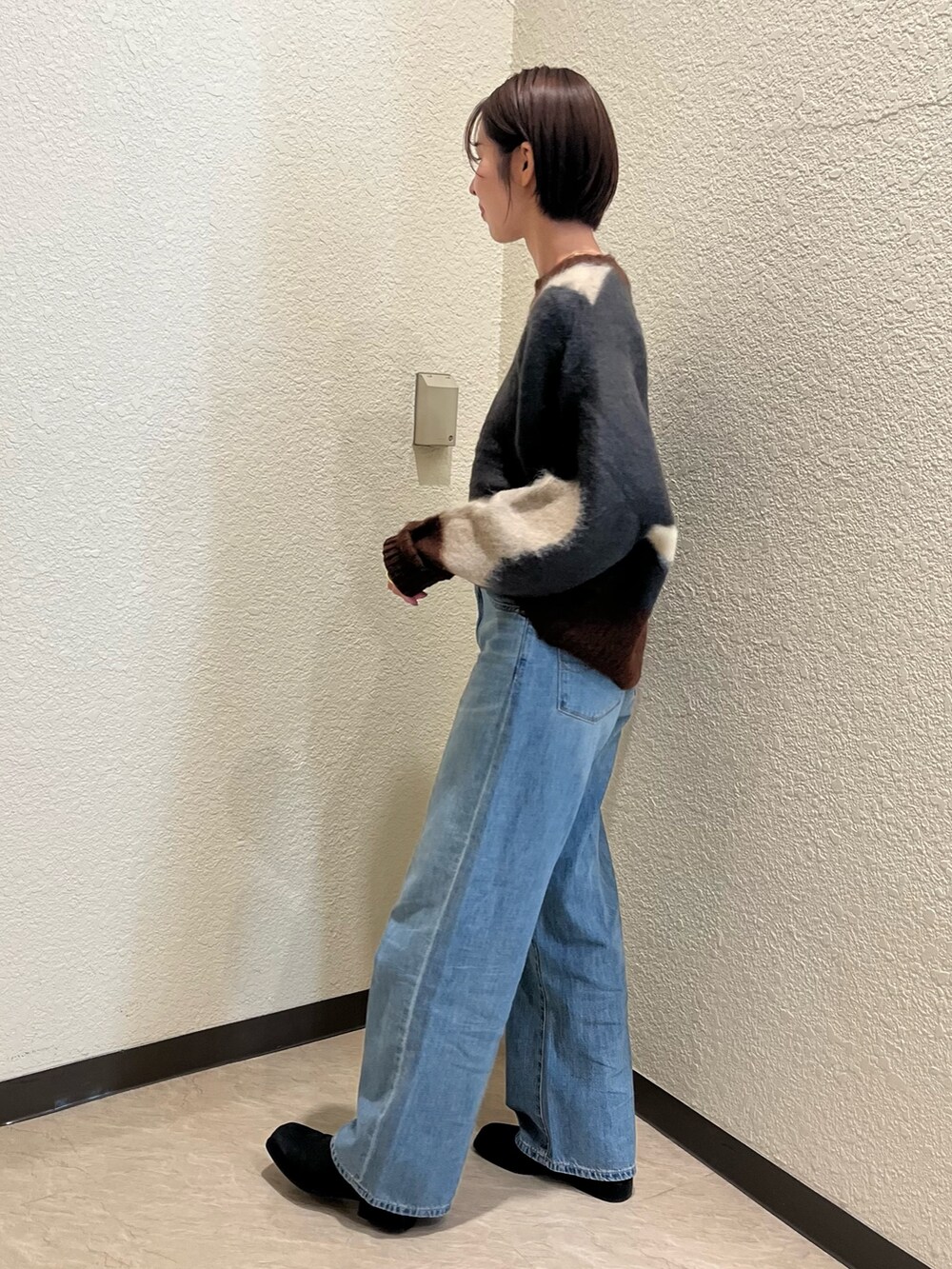 グレー系のニット/セーター、ブルー系のデニムパンツを着用したレディースの秋コーディネートの2枚目の写真