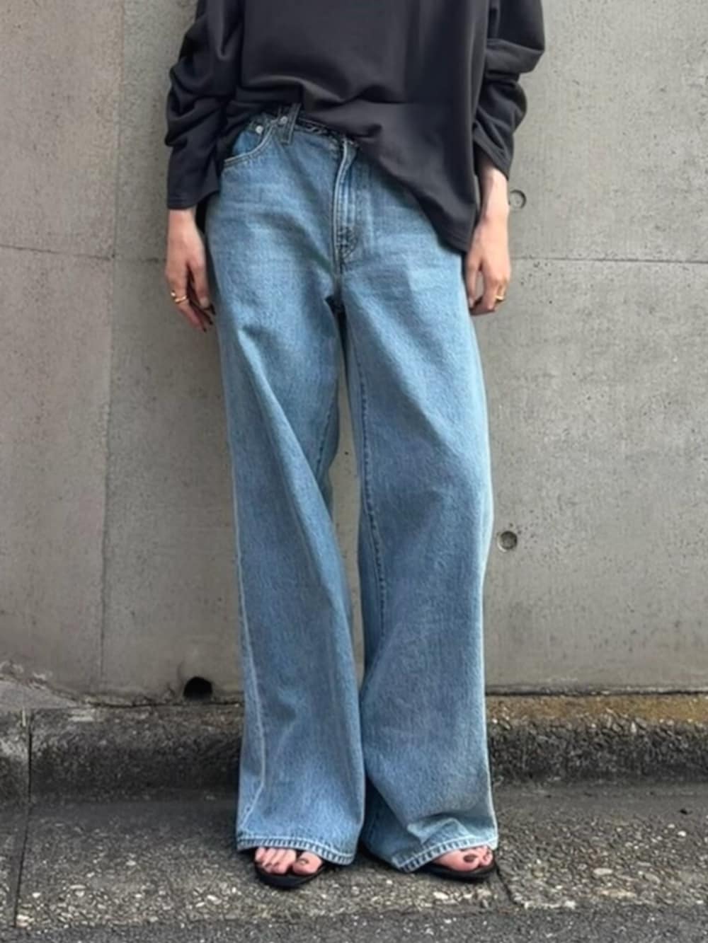 グレー系のスウェット、ブルー系のデニムパンツを着用したレディースの夏コーディネートの5枚目の写真