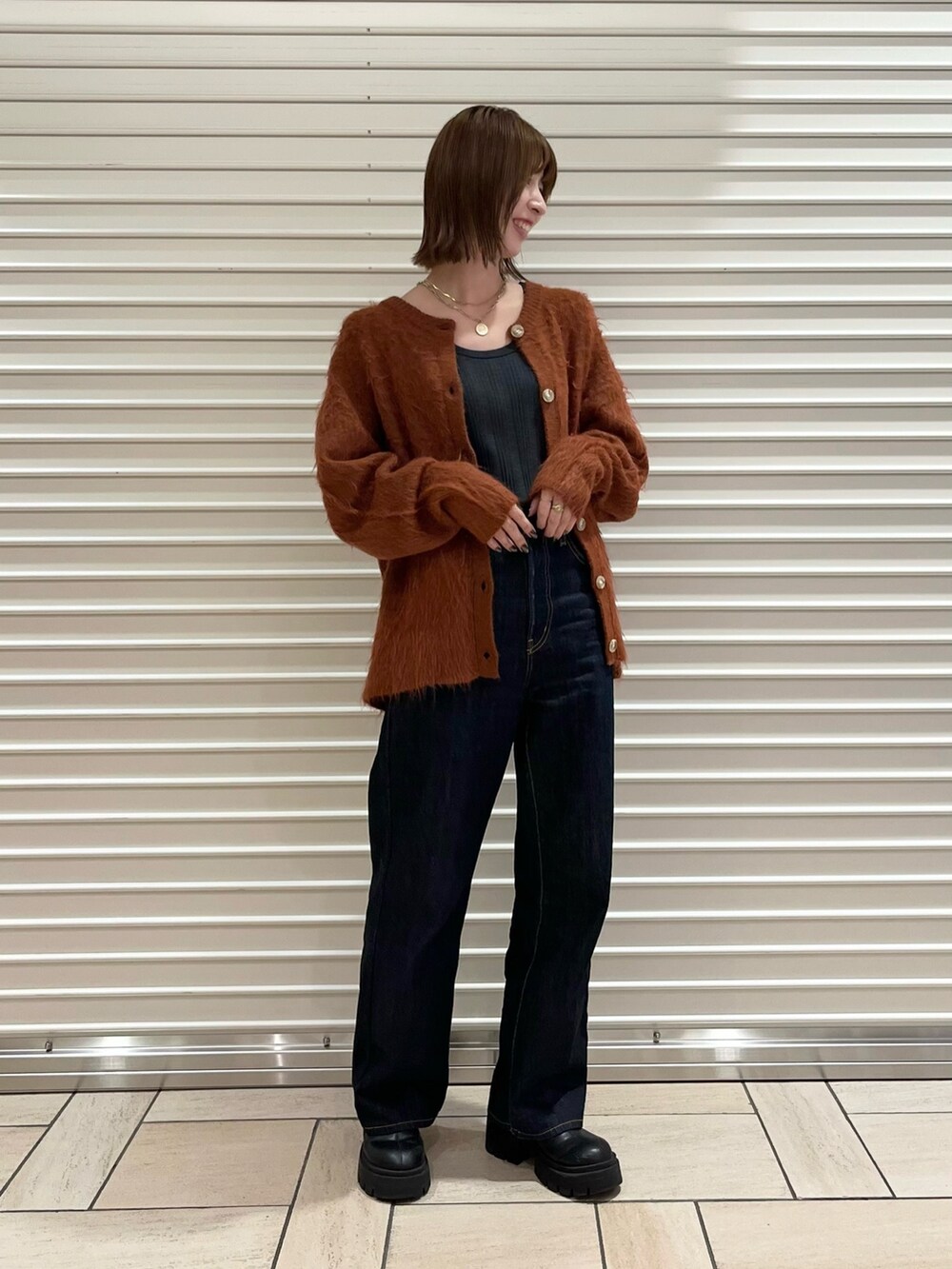 グレー系のTシャツ/カットソー、オレンジ系のカーディガン/ボレロ、ブルー系のデニムパンツを着用したレディースの秋コーディネートの3枚目の写真