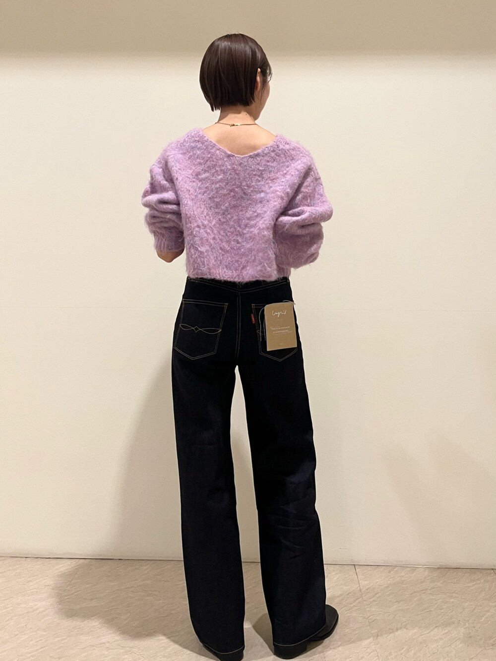 パープル系のニット/セーター、ブルー系のデニムパンツを着用したレディースの秋コーディネートの3枚目の写真