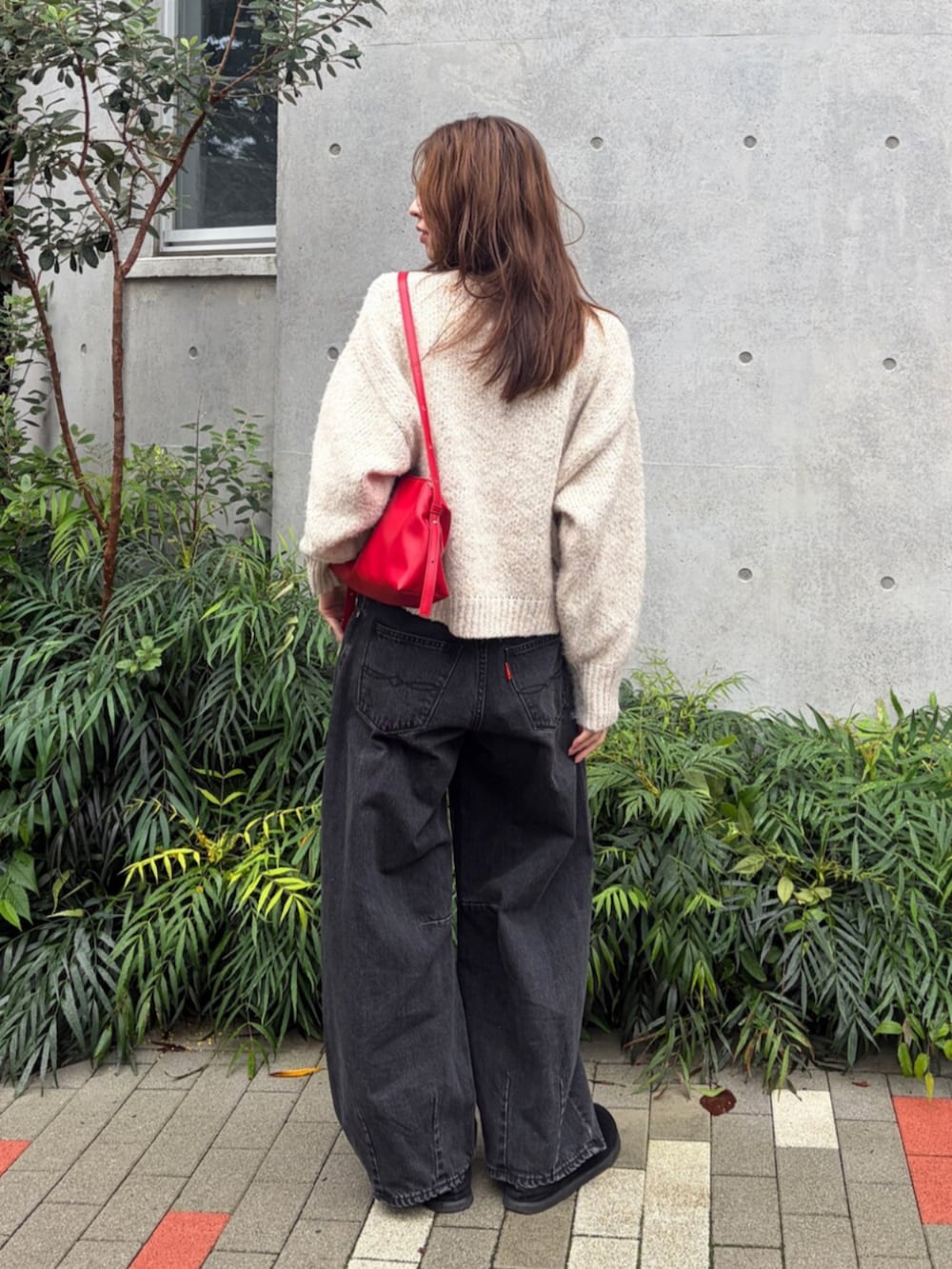 ホワイト系のニット/セーター、ブラック系のデニムパンツ、レッド系のハンドバッグを着用したレディースの秋コーディネートの3枚目の写真