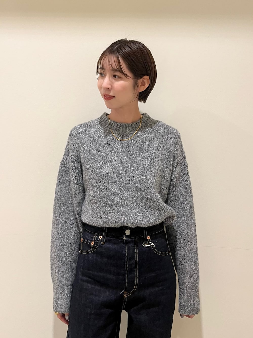 グレー系のニット/セーター、ブルー系のデニムパンツを着用したレディースの秋コーディネートの4枚目の写真