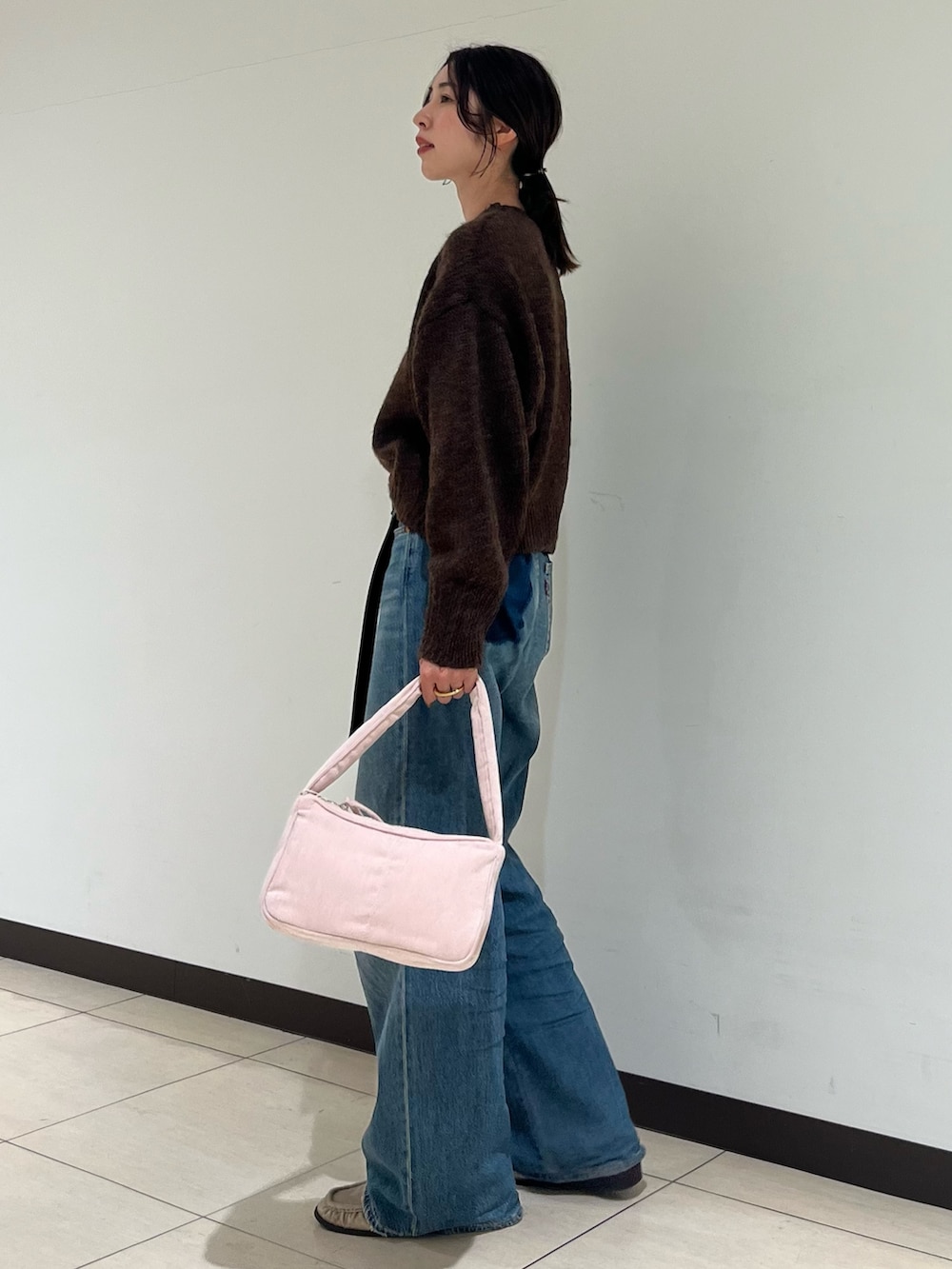ブラウン系のニット/セーター、ブルー系のデニムパンツ、ピンク系のハンドバッグを着用したレディースの秋コーディネートの2枚目の写真