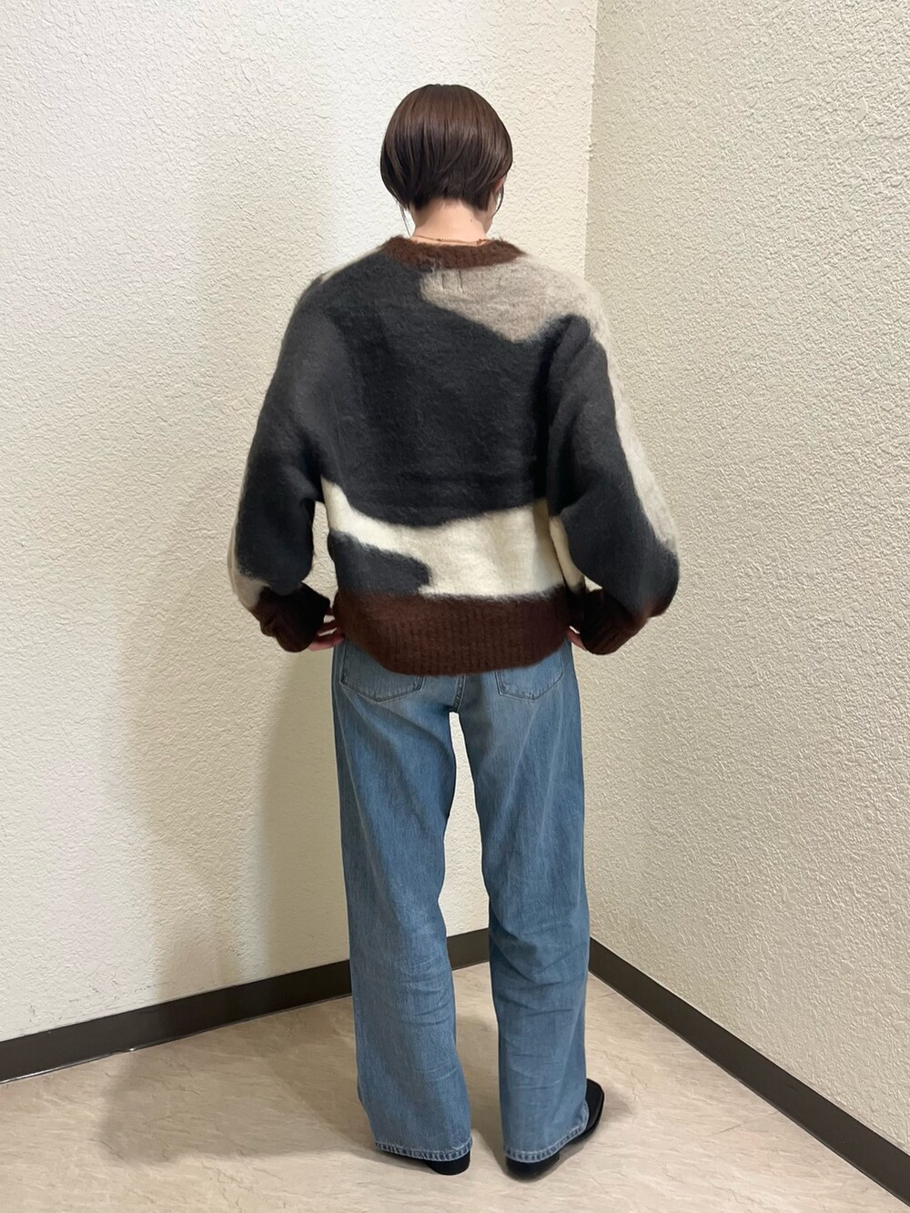 グレー系のニット/セーター、ブルー系のデニムパンツを着用したレディースの秋コーディネートの3枚目の写真